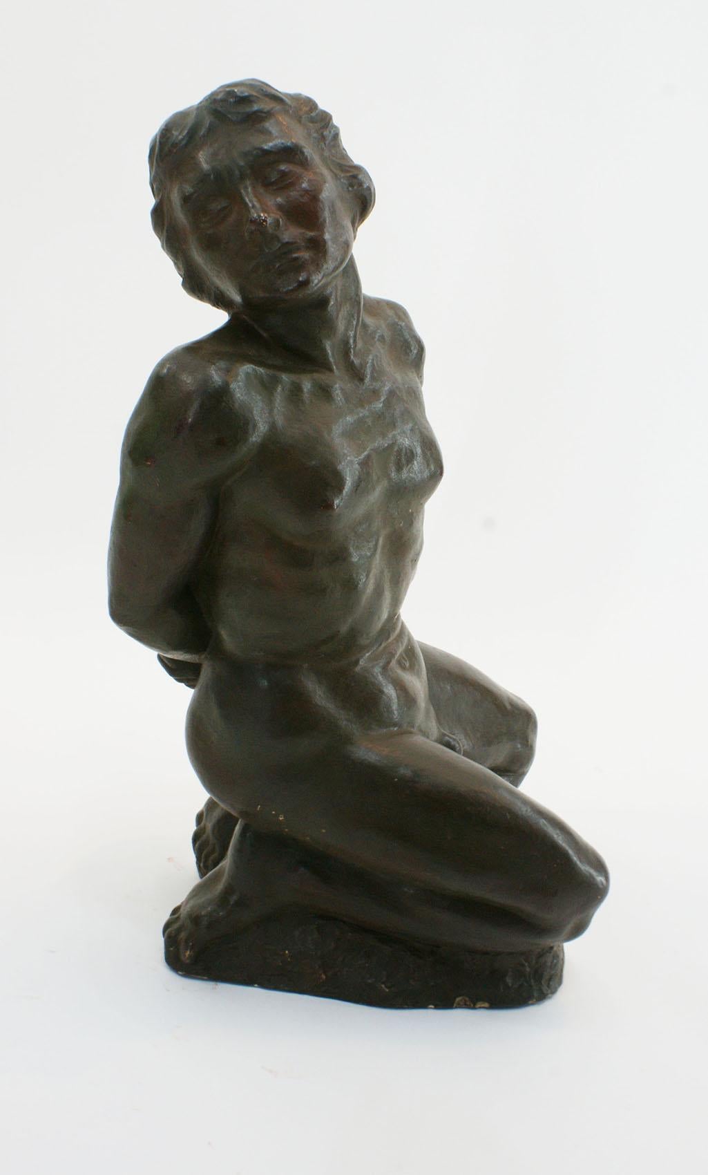 French Art Deco terracotta sculpture in black patina color by R.Brageu representing a naked athletic young man on his knees, in an attitude of submission. This work focuses on the human anatomy, using an Expressionist approach. The sculpture is