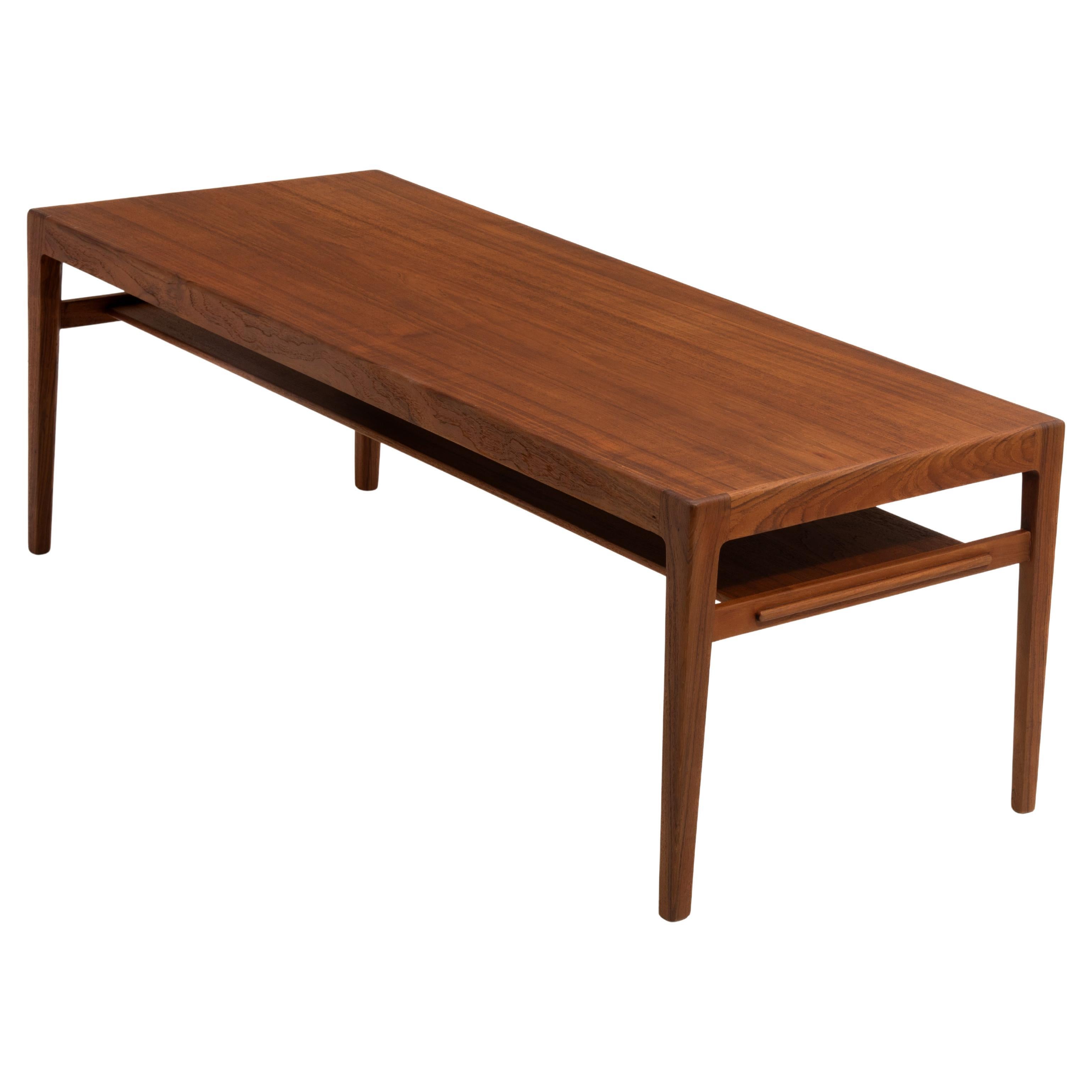 A mid century teak coffee table with magazine shelf designed by Eske Kristensen and made by master cabinet maker Ludvig Pontoppidan. Copenhagen, Denmark. The table is beautifully finished with elegant edges and tapered legs, an elegant design with