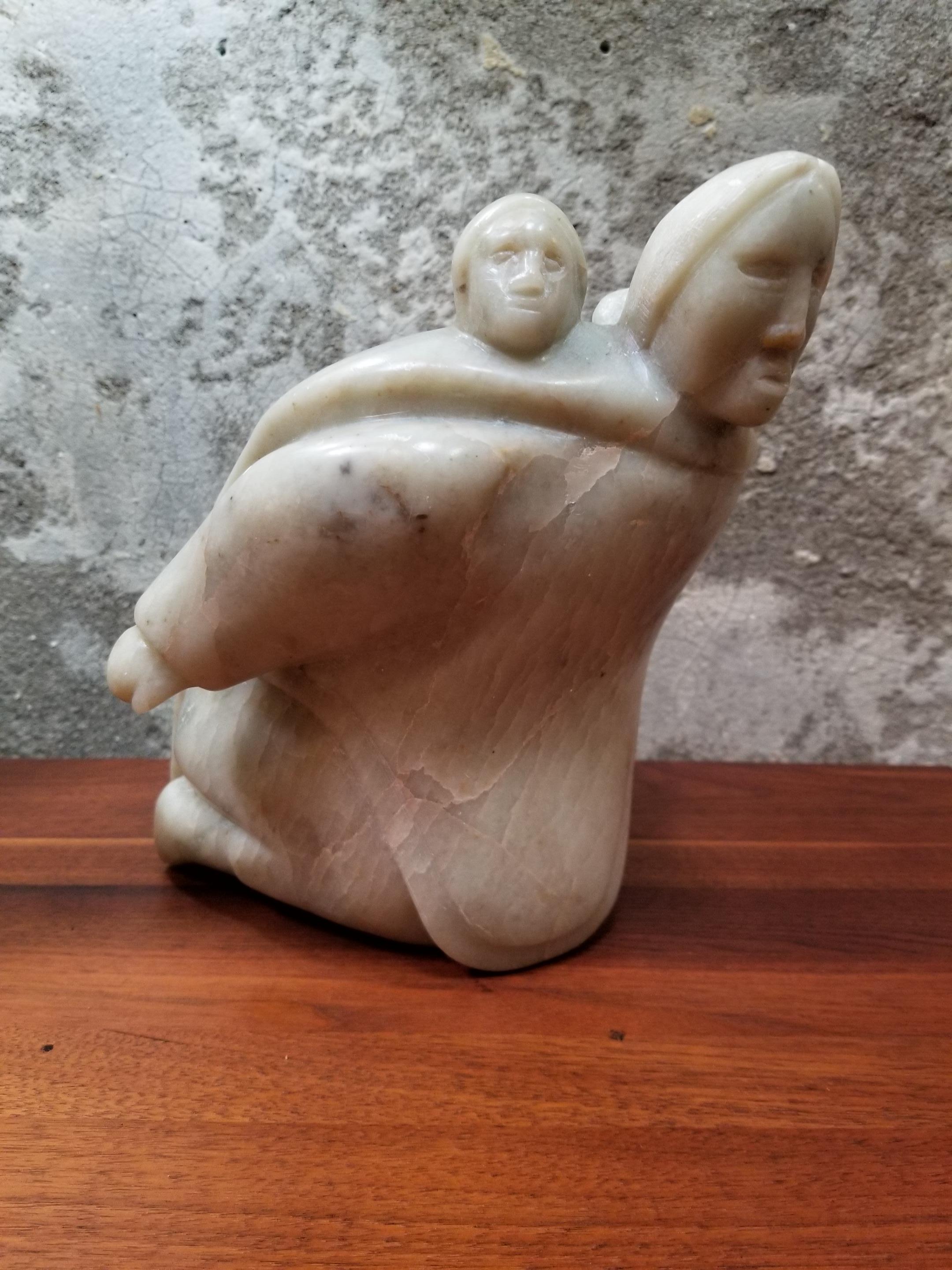 An Eskimo/Inuit hand carved soapstone sculpture of a mother and child. Signed and dated 1974. Beautiful marbling pattern to less common off-white soapstone. Retains original paper tag. Stands 9.5 inches tall.