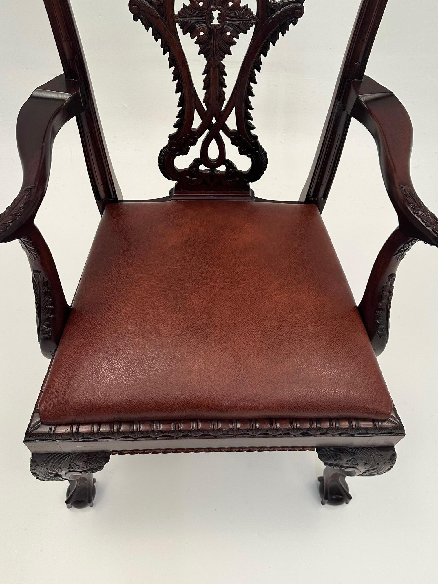 Wunderschöner handgeschnitzter englischer Sessel aus dunklem Mahagoni im Chippendale-Stil mit verzierter Rückenlehne und Kugel- und Klauenfüßen.  Neuerer, reich gepolsterter Sitz aus Leder.
Armhöhe 28