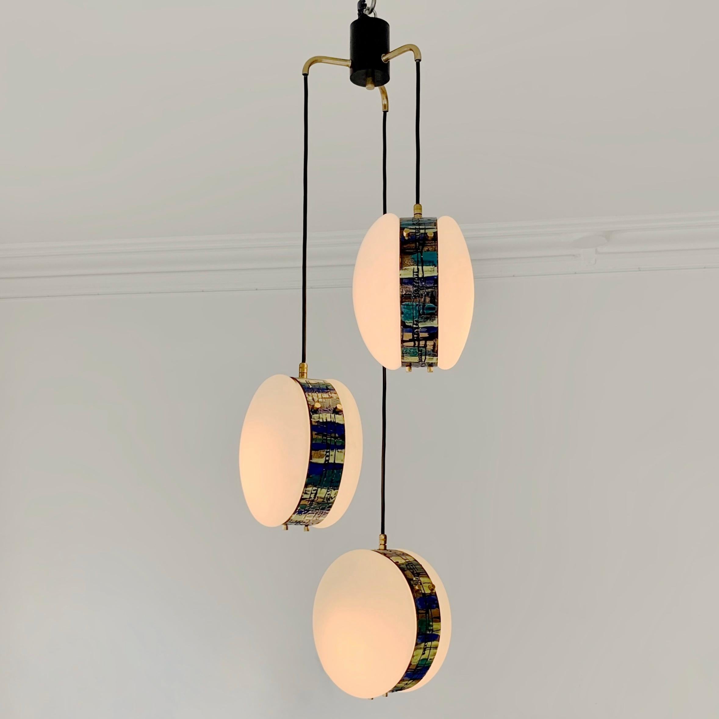 Rare Angelo Brotto 3-lights chandelier for Esperia, circa 1960, Italy.
Each pendant made of two parts of opaline glass attached by a metal circle with an enamelled hand-crafted abstract multi-colored decor, brass decoratives screws and details,