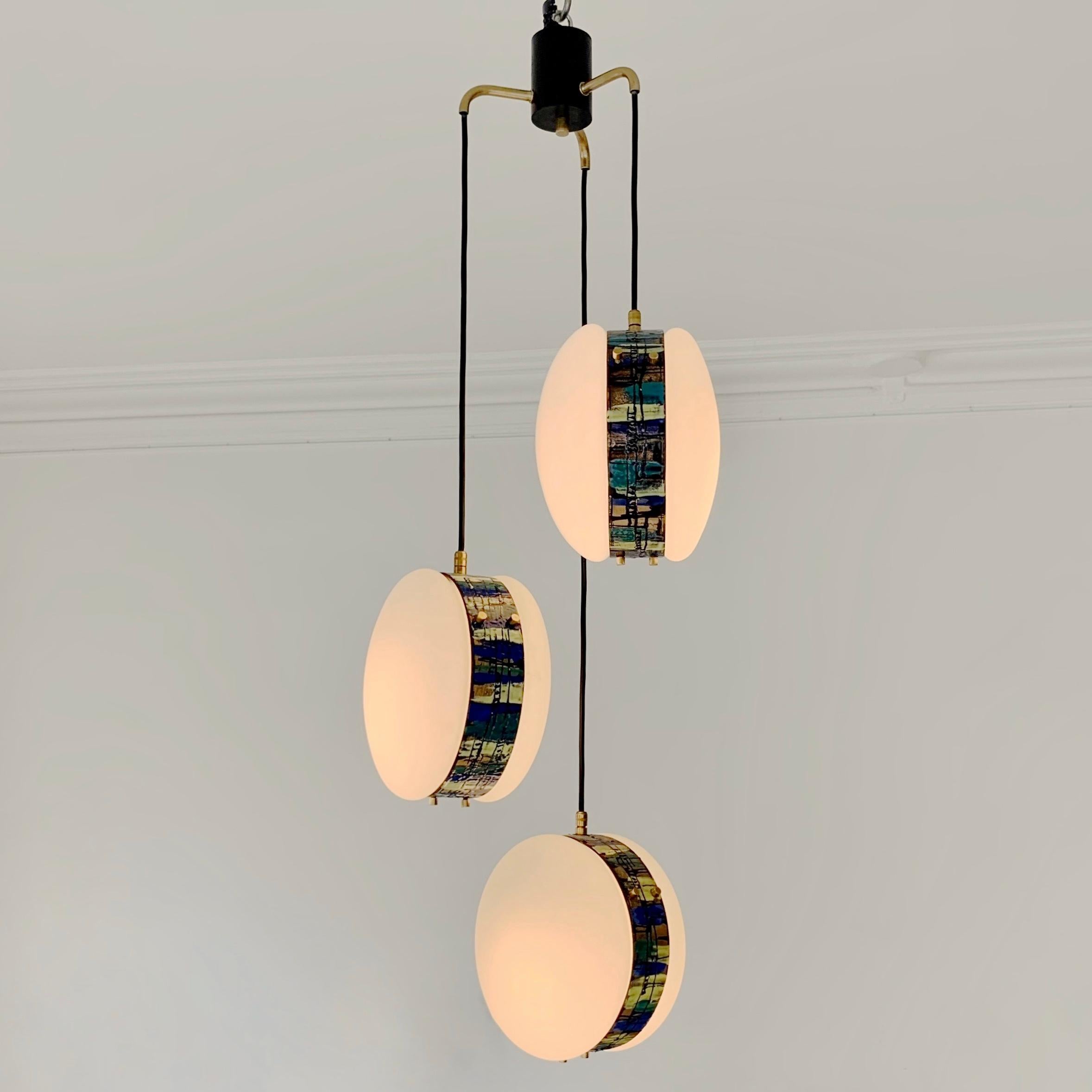 Rare Angelo Brotto 3-lights pendant lamp for Esperia, circa 1960, Italy.
Each pendant made of two parts of opaline glass attached by a metal circle with an enamelled hand-crafted abstract multi-colored decor, brass decoratives screws and details,