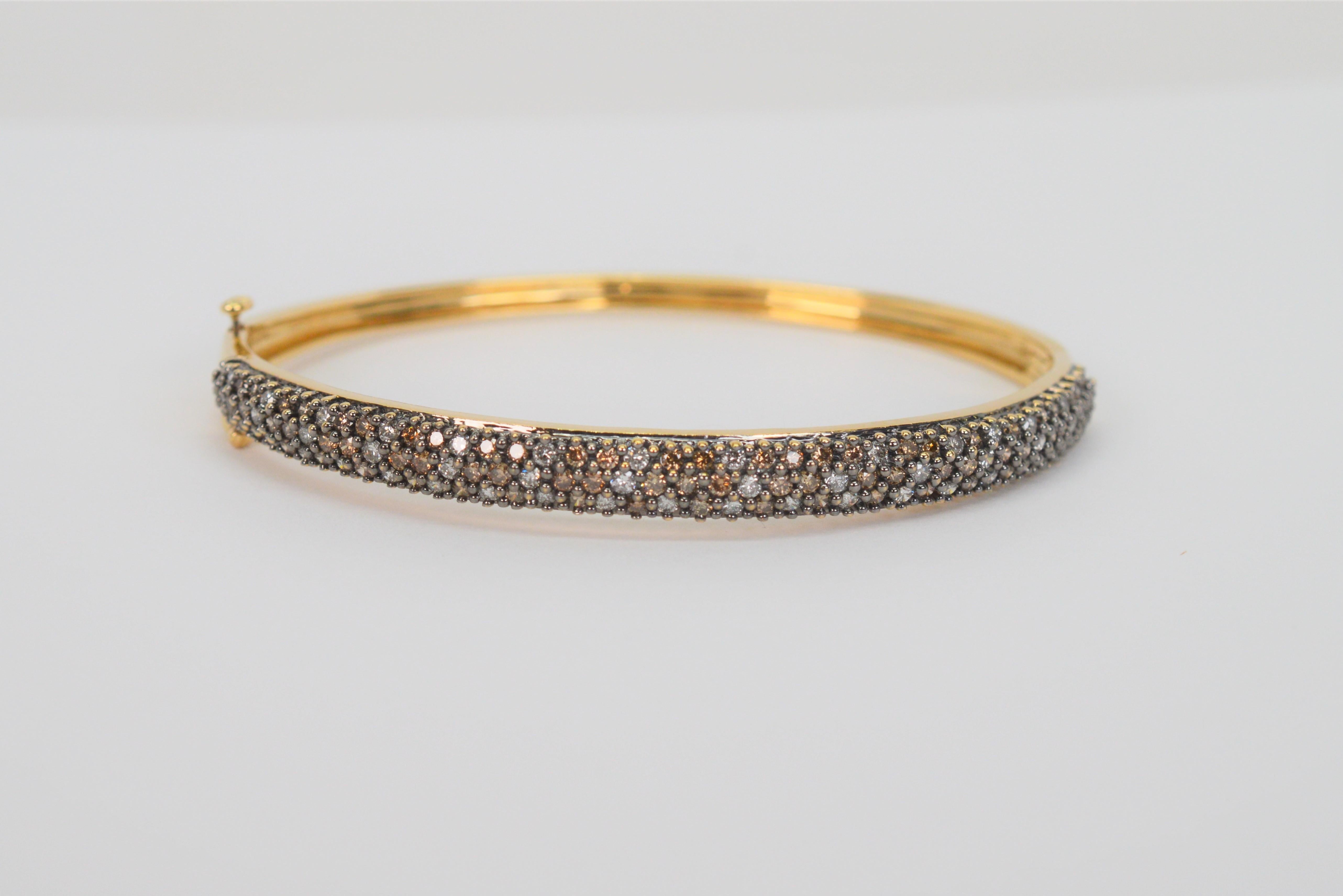 Love the sparking sophistication of this slender bangle bracelet adorned with a dazzling display of hand set pave espresso and white diamonds in 14 karat yellow gold. The front placket of this elegant bracelet has over one carat of diamonds, 1.365