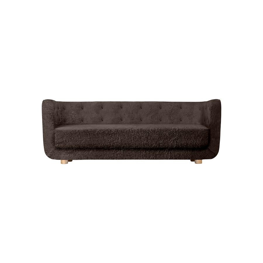 Espresso sheepskin and natural oak Vilhelm sofa by Lassen
Dimensions: W 217 x D 88 x H 80 cm 
Materials: Sheepskin, oak.

Vilhelm is a beautiful padded three-seater sofa designed by Flemming Lassen in 1935. A sofa must be able to function in