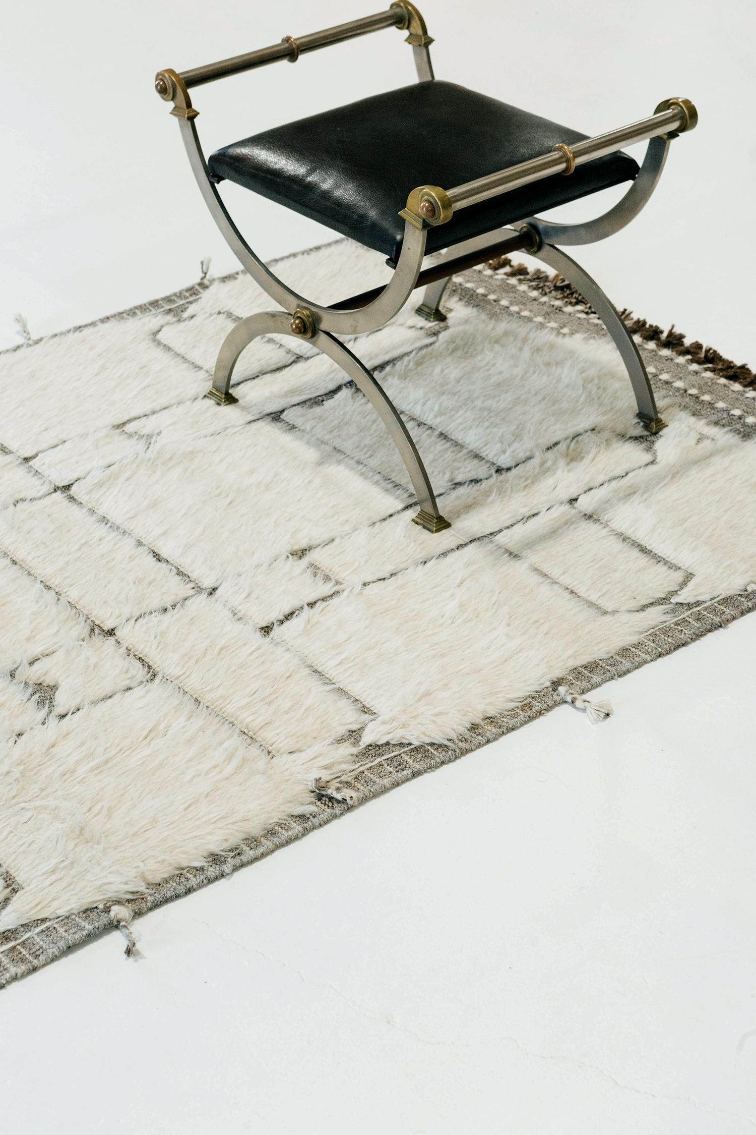 Essaouina' is a beautifully textured rug with embossed designs inspired from the Atlas Mountains of Morocco. Natural gray motifs surrounded by ivory shag and tasseled borders make for a great contemporary interpretation for the modern design world.