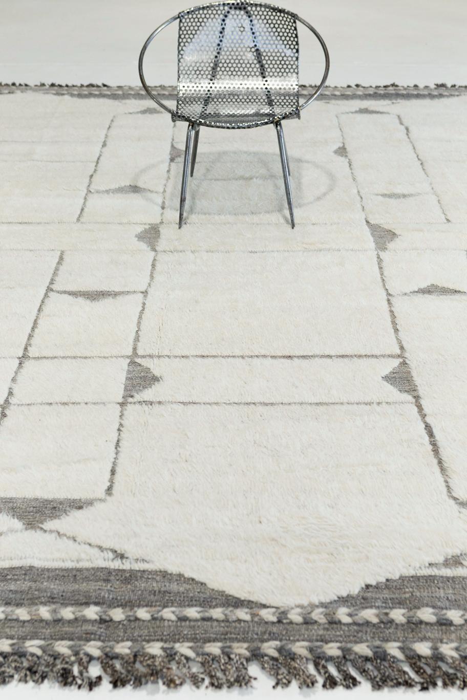 Essaouina is a beautifully textured rug with embossed designs inspired from the Atlas Mountains of Morocco. Natural gray motifs surrounded by ivory shag and tasseled borders make for a great contemporary interpretation for the modern design world.