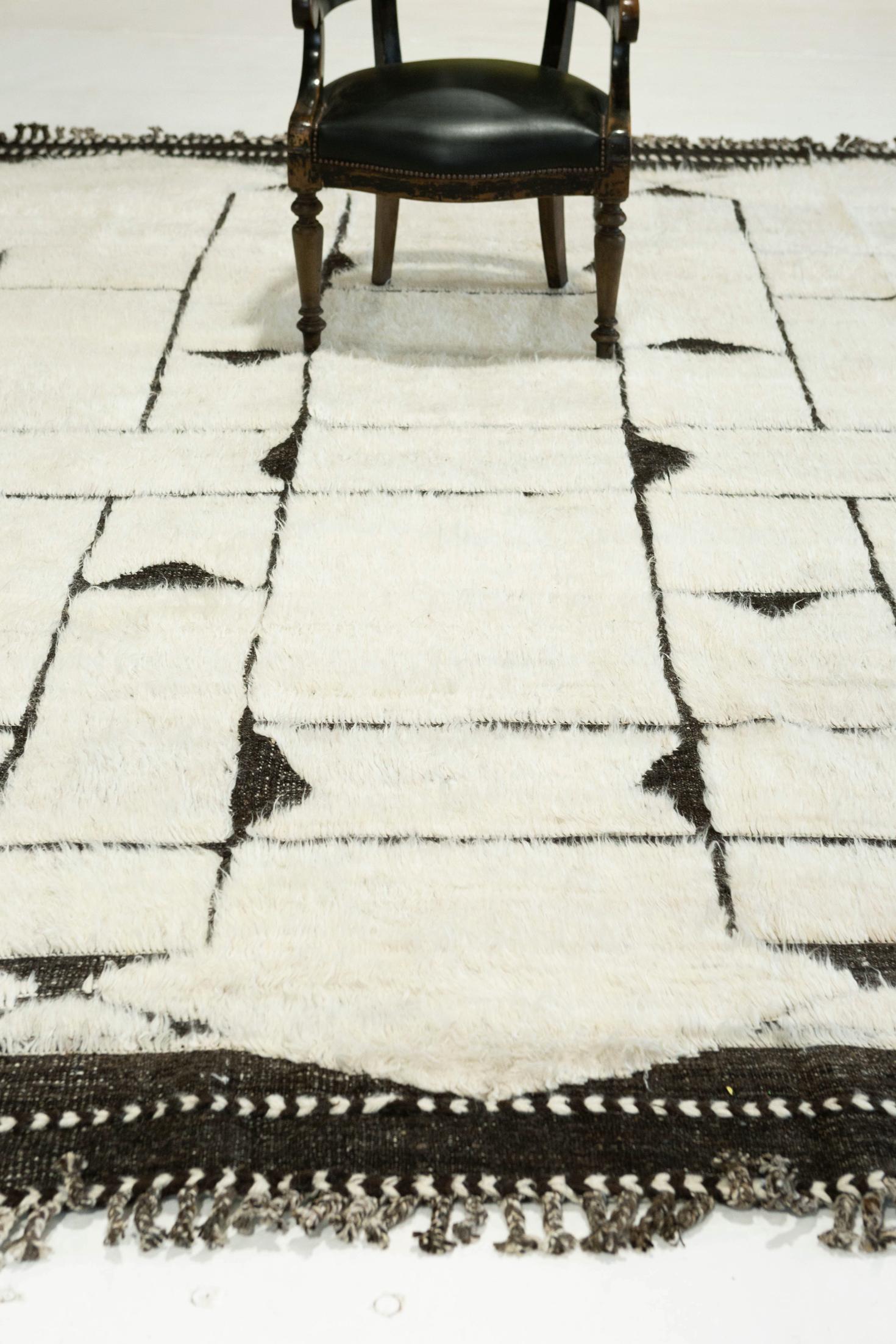 Essaouina' is a beautifully textured rug with embossed designs inspired from the Atlas Mountains of Morocco. Natural black motifs surrounded by ivory shag and tasseled borders make for a great contemporary interpretation for the modern design world.