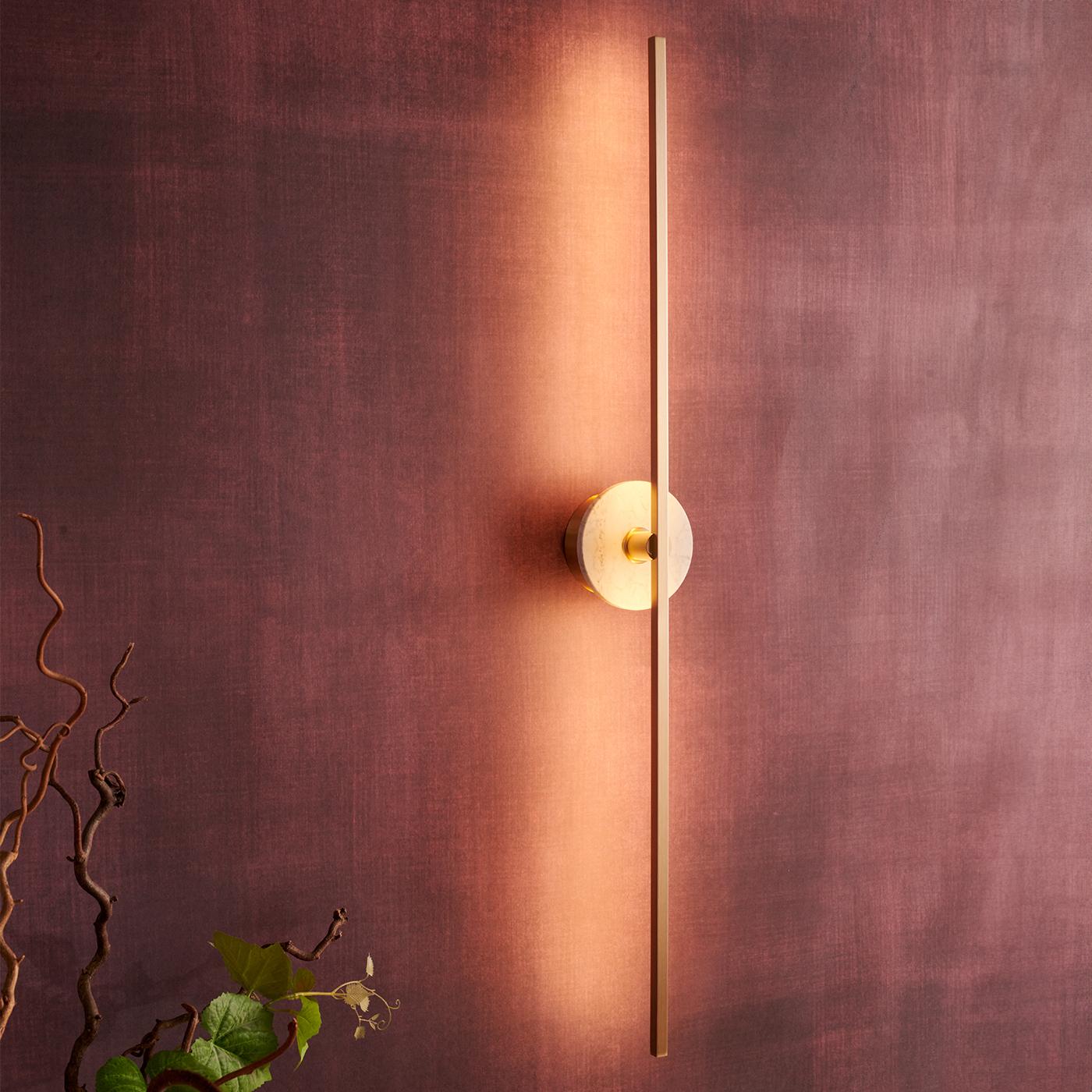 El aplique de pared Grand stick es un accesorio de iluminación contemporáneo que presenta un diseño minimalista con finos perfiles de latón y avanzada tecnología LED. Emite una luz cálida y difusa que añade un ambiente acogedor y acogedor a