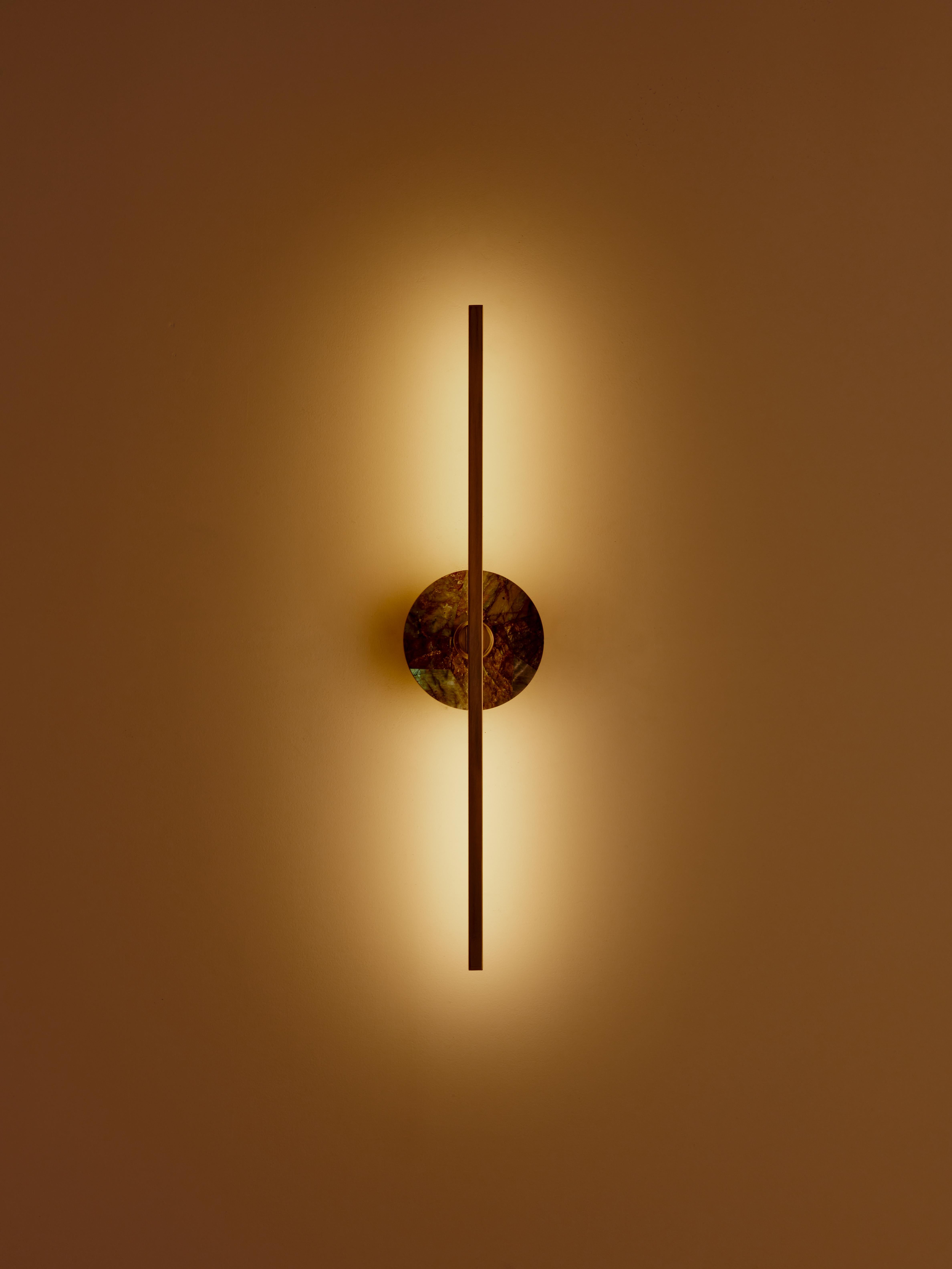 El aplique de pared Elite Stick combina el minimalismo de los finos perfiles de latón con la funcionalidad y la potencia de la tecnología led, ofreciendo una luz cálida y difusa. La malaquita, puro elemento decorativo, embellece la estructura del