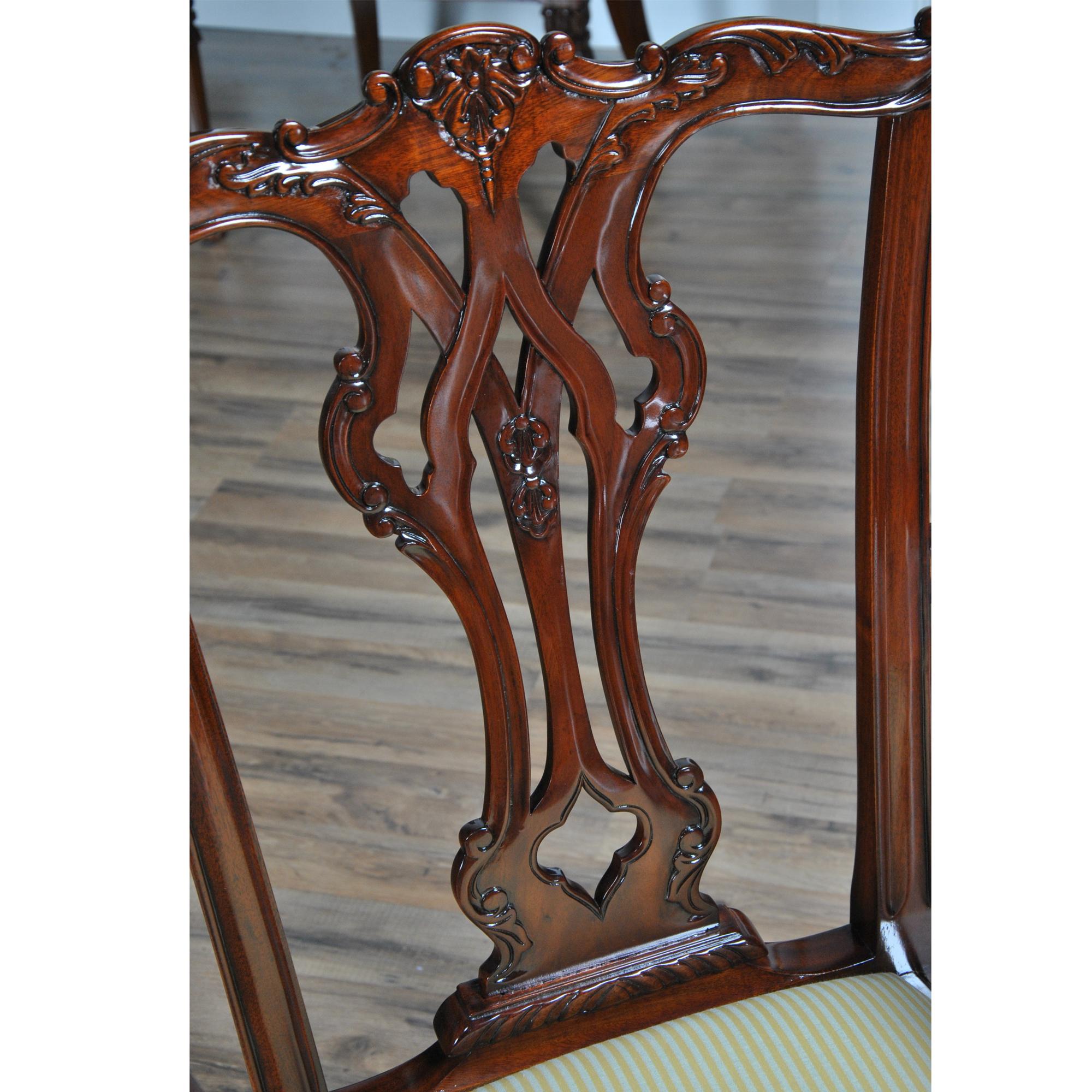 A luxurious set of 10 Essex Chippendale Chairs, the set consisting of 2 arm chairs and 8 side chairs. Each chair features a highly carved and intricately serpentine crest rail and a carved and pierced back splat. The arm chair has scrolled arms at a