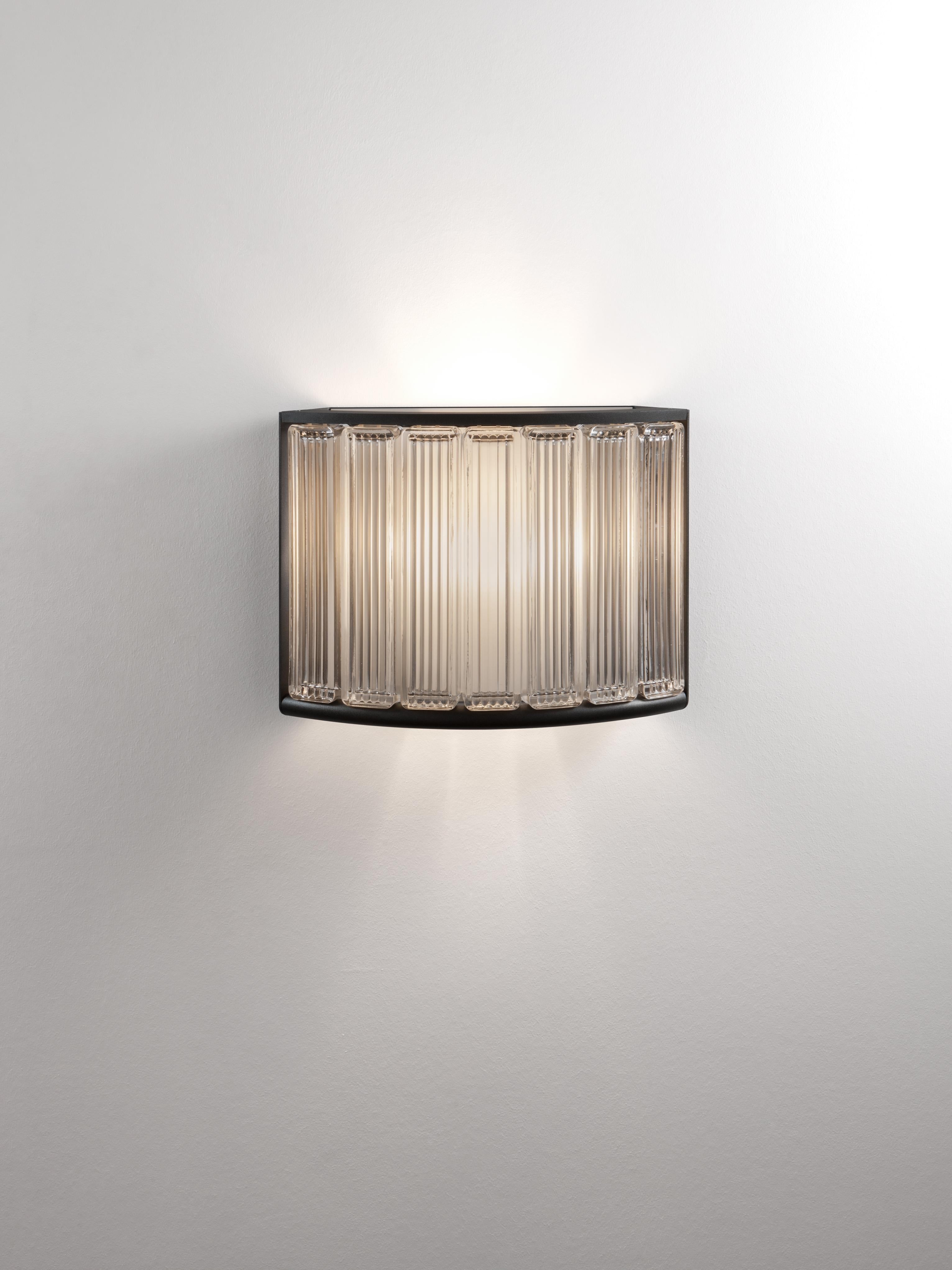 Estadio wall lamp by Miguel Milá
Dimensions: D 44 x W 14 x H 33 cm
Materials: Metal, glass.

Originally designed for the Olympic Stadium in Barcelona 1992, this curved line of lighting ennobles the space around it. The visible sides of its structure