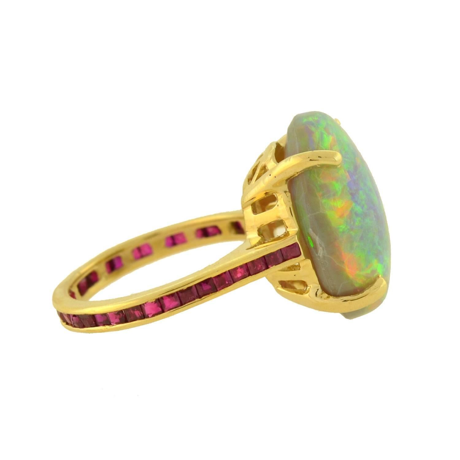 An outstanding Estate opal ring! This exquisite piece is crafted in 14kt yellow gold and features a single large opal at the center of a decorative mounting. The cabochon cut opal is simply mesmerizing, displaying an array of iridescent colors that