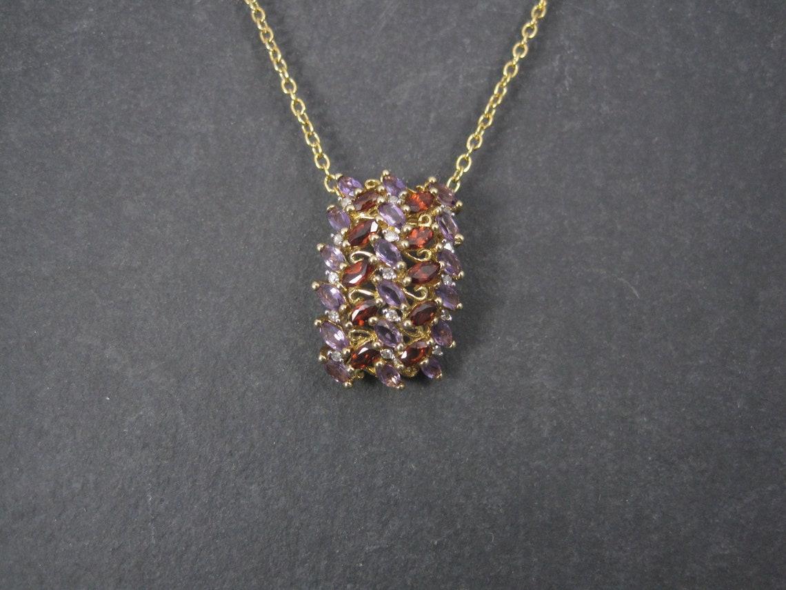 This beautiful pendant is 10k yellow gold.
It features an estimated 1 carat in marquise-cut amethysts, .50 carats in marquise-cut garnets, and 0.3 carats in round diamonds.

Measurements: 5/8 by 15/16 of an inch

Condition: Excellent

*Note, the