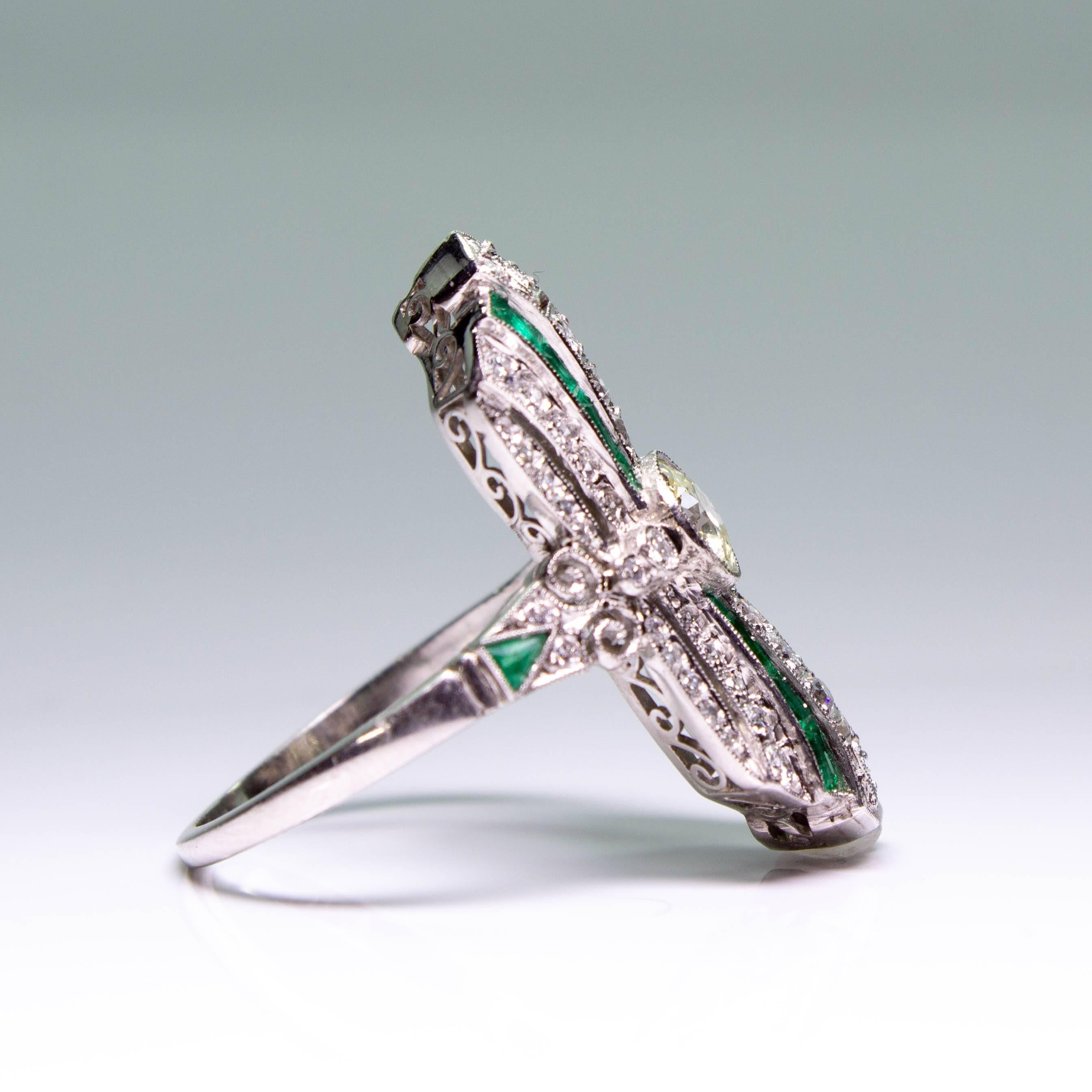 Composition: Platinum
Stones:
•	1 Old mine cut diamonds of J-VS2 quality that weigh 0.51ctw. 
•	56 Old European cut diamonds of I/J-VS2 quality that weigh 0.77ctw.
•	18 natural calibrated cut emeralds that weigh 0.69ctw.
Ring size: 7 ¾    
Ring