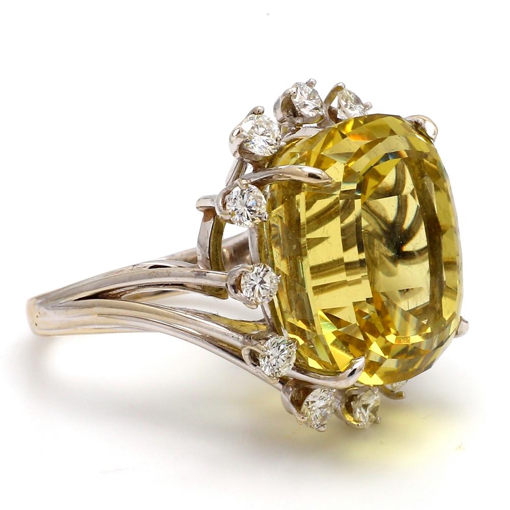 14K white gold cocktail ring. Center stone is one (1) cushion cut yellow beryl weighing 31.01ct. Center stone is surrounded by twelve (12) round brilliant cut diamonds weighing 1.80ctw.  Ring weighs 7.8 grams and is a size 7.
All questions