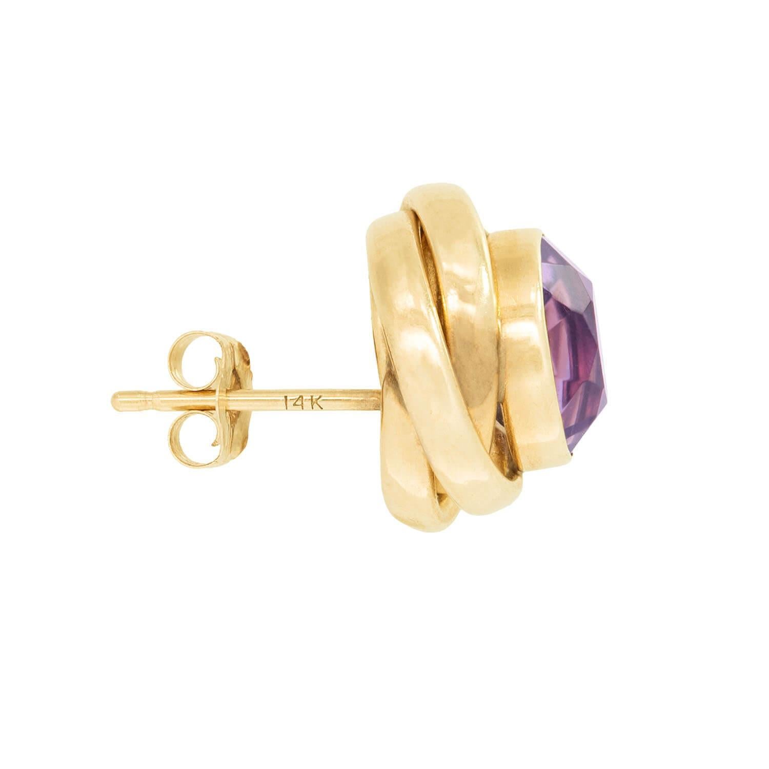 A fabulous pair of knot earrings! Crafted in 14k vibrant yellow gold, each earring represents a dainty knot. Each earring is centered by a round cut amethyst held within a bezel setting. The rich purple hue of the amethyst stones wonderfully
