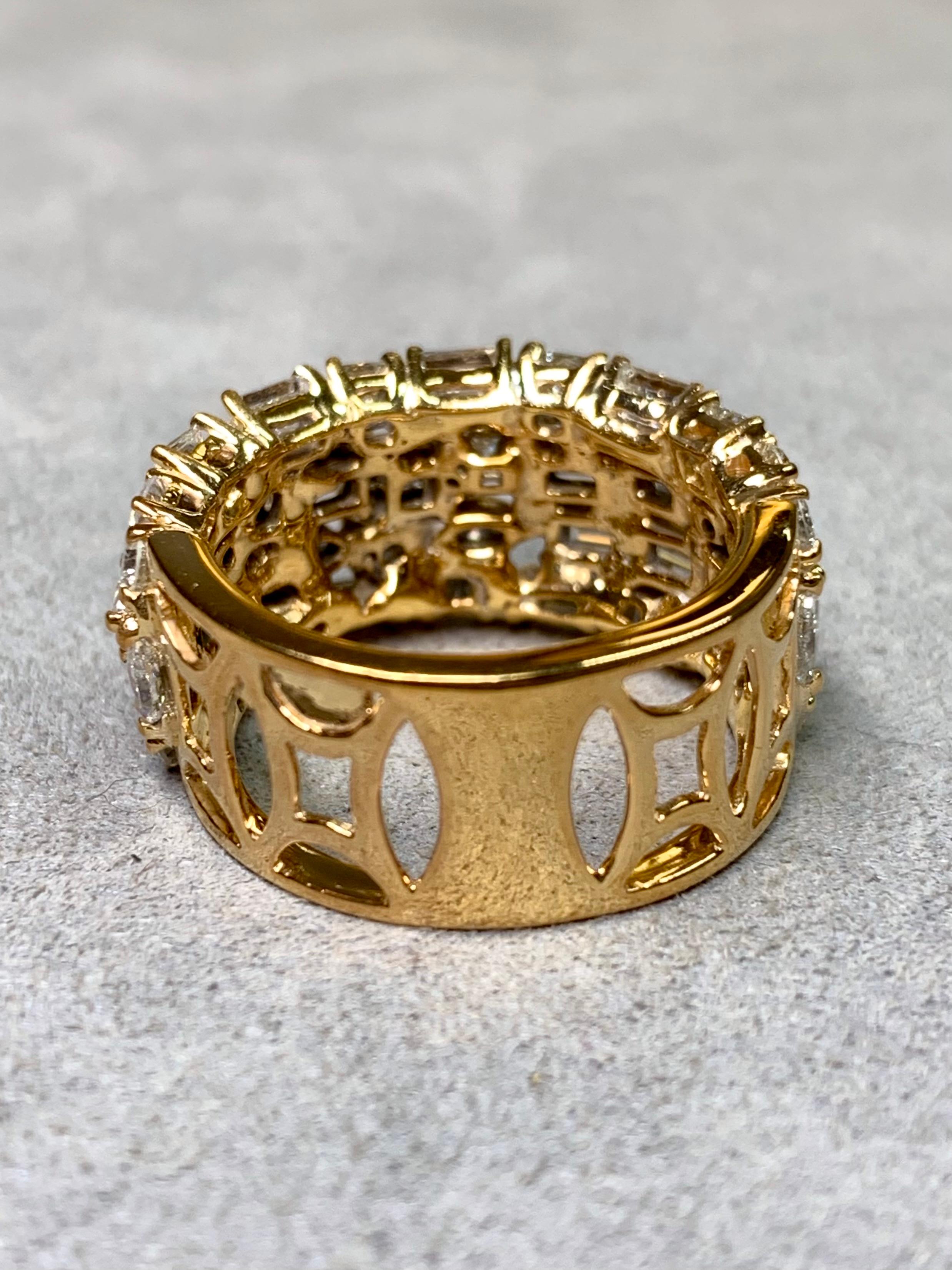 
A glamorous estate band ring crafted in rich 14 karat yellow gold, shimmering with an extraordinary mosaic of diamond cuts. Four bold rows of alternating baguette, princess cut, marquise, and round brilliant diamonds create a dazzling tapestry of