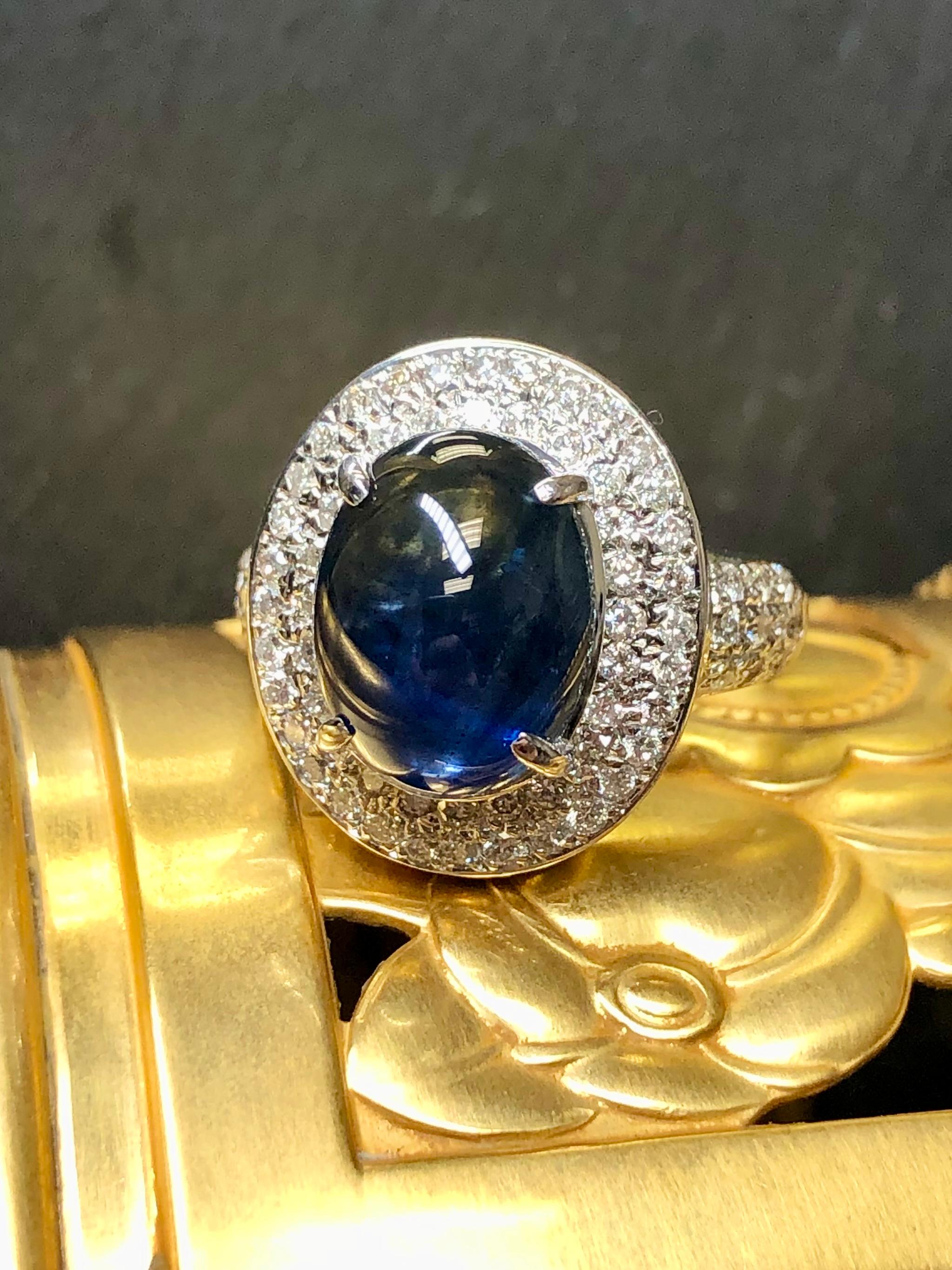 
A beautiful and impressive ring done in 14K white gold and centered with an approximately 8.36ct (12.92 9.95x6.05) cabochon sapphire exhibiting a desirable soft, deep blue color. Surrounding the center stone is approximately 1.56cttw in I-J Vs1-2
