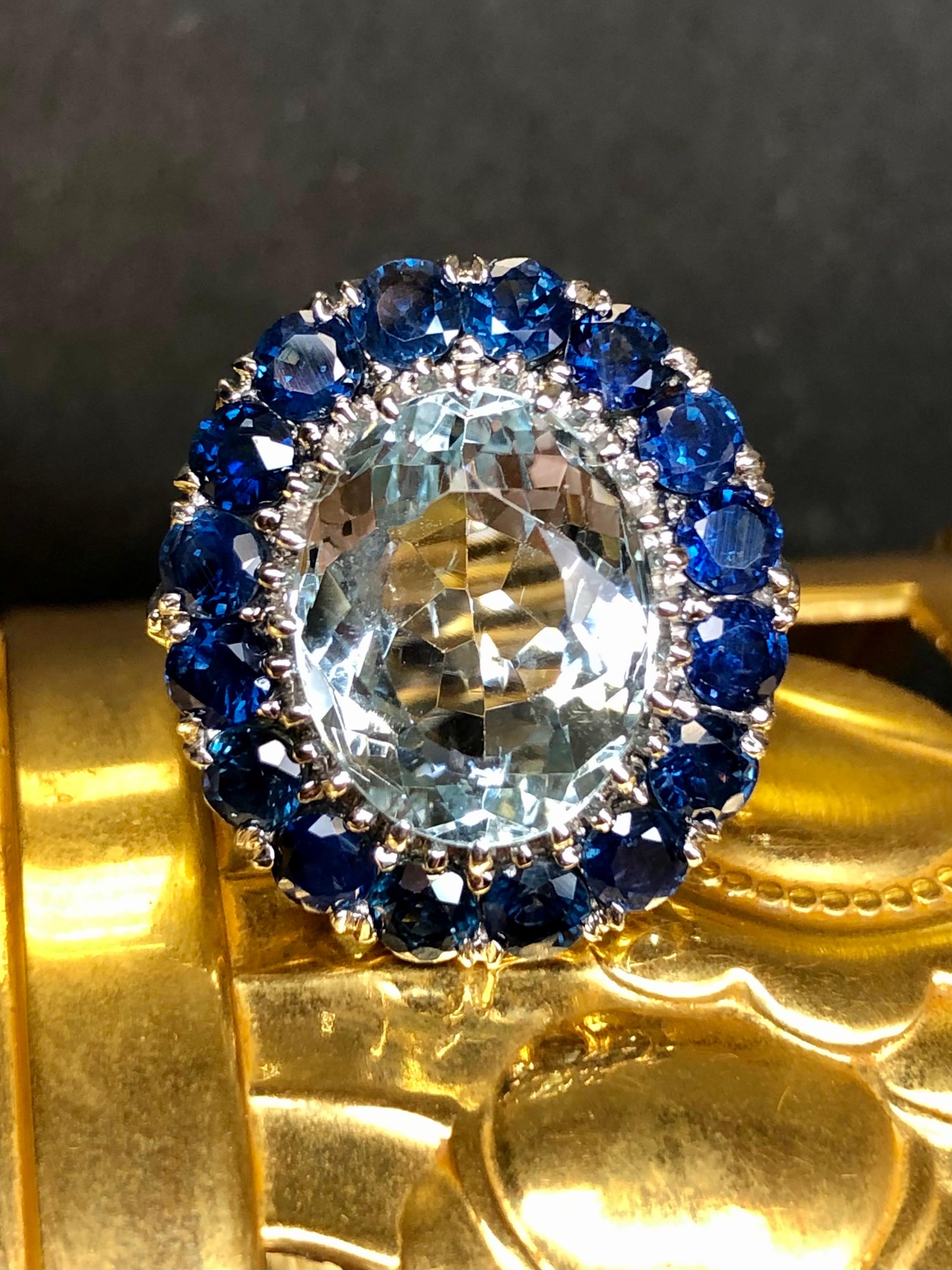 An absolutely stunning cocktail ring done in 14K white gold centered by an approximately 6ct natural oval aquamarine surrounded by approximately 3.50cttw in large and bright natural royal blue sapphires. A beautifully crafted piece that would be a