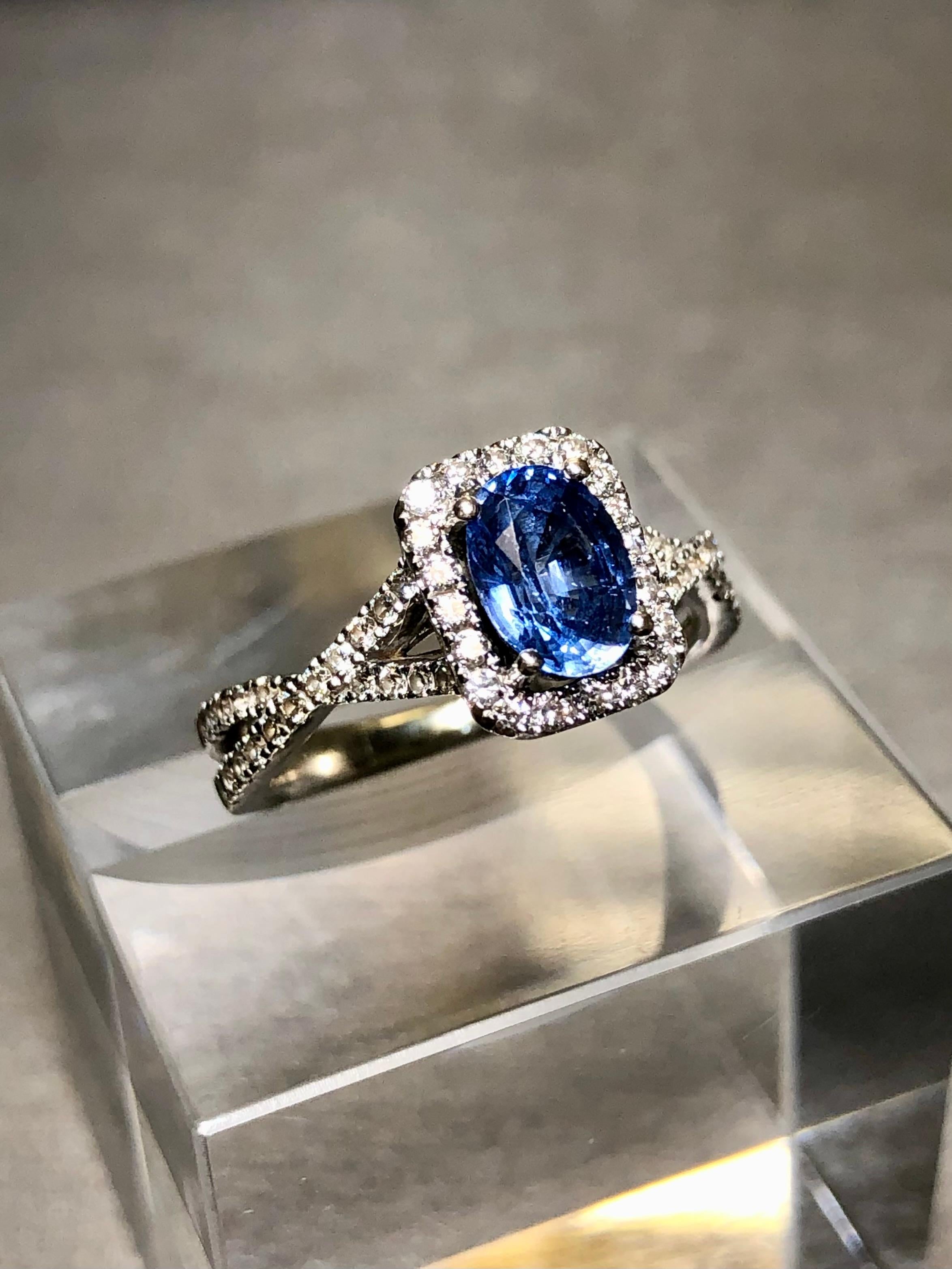 An elegant solitaire ring done in 14K white gold centered by a gorgeous cornflower blue natural oval cut sapphire weighing approximately 1ct. Bead set down the sides is approximately .60cttw in H-J color Vs2-Si1 clarity round