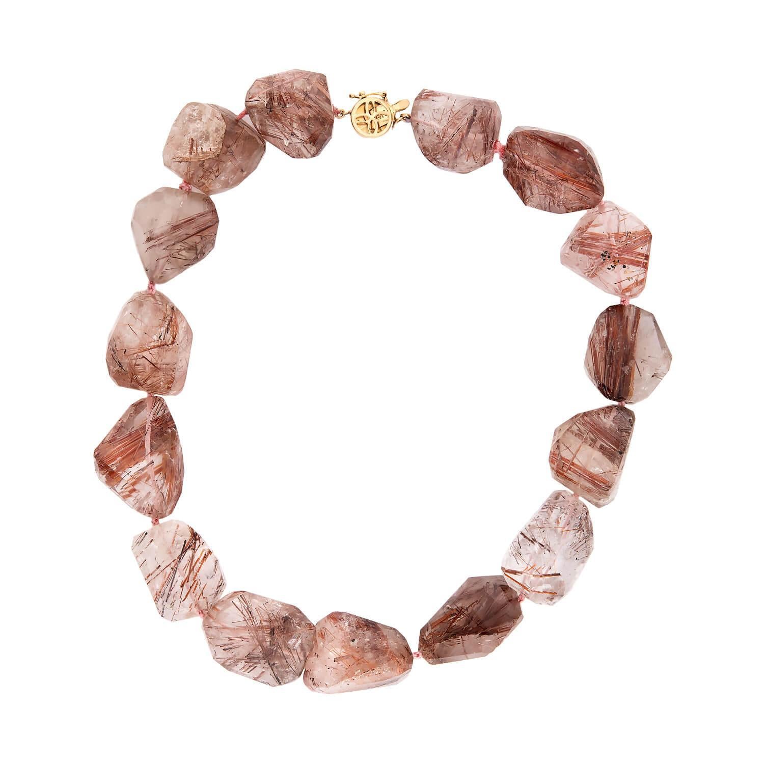 Un collier de perles magnifique et unique ! Cette jolie pièce présente une rangée de perles en cristal de quartz rutilé, qui sont enfilées sur un cordon blanc. Le quartz varie en couleur et en forme, et présente des couleurs translucides brunes et