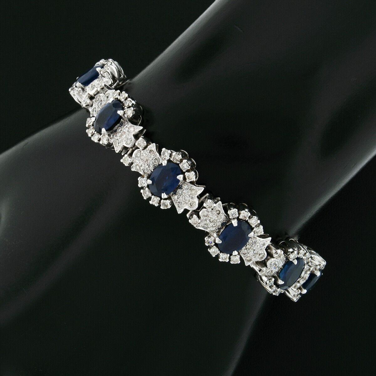 This magnificent statement piece is very well crafted in solid 14k white gold and is set with fine quality diamonds and sapphires throughout. The bracelet features 12 consistent floral links, with each being set with an oval cut sapphire that's