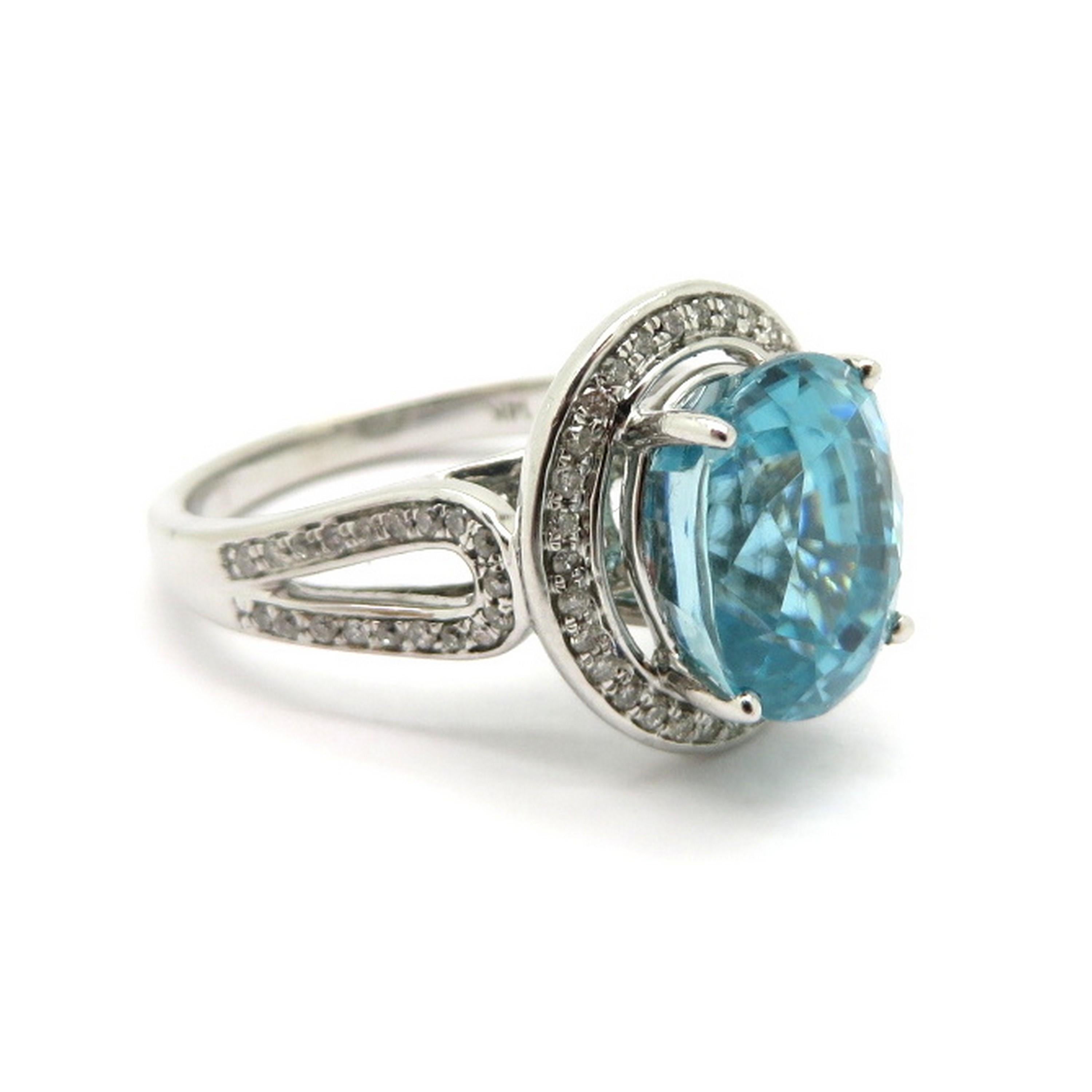 Estate 14K white gold 5.00 carat blue zircon and diamond halo fashion ring. Showcasing one fine quality oval-shaped blue zircon, four prong set, weighing approximately 5.00 carats. Accented with 70 bead set round brilliant cut diamonds weighing a