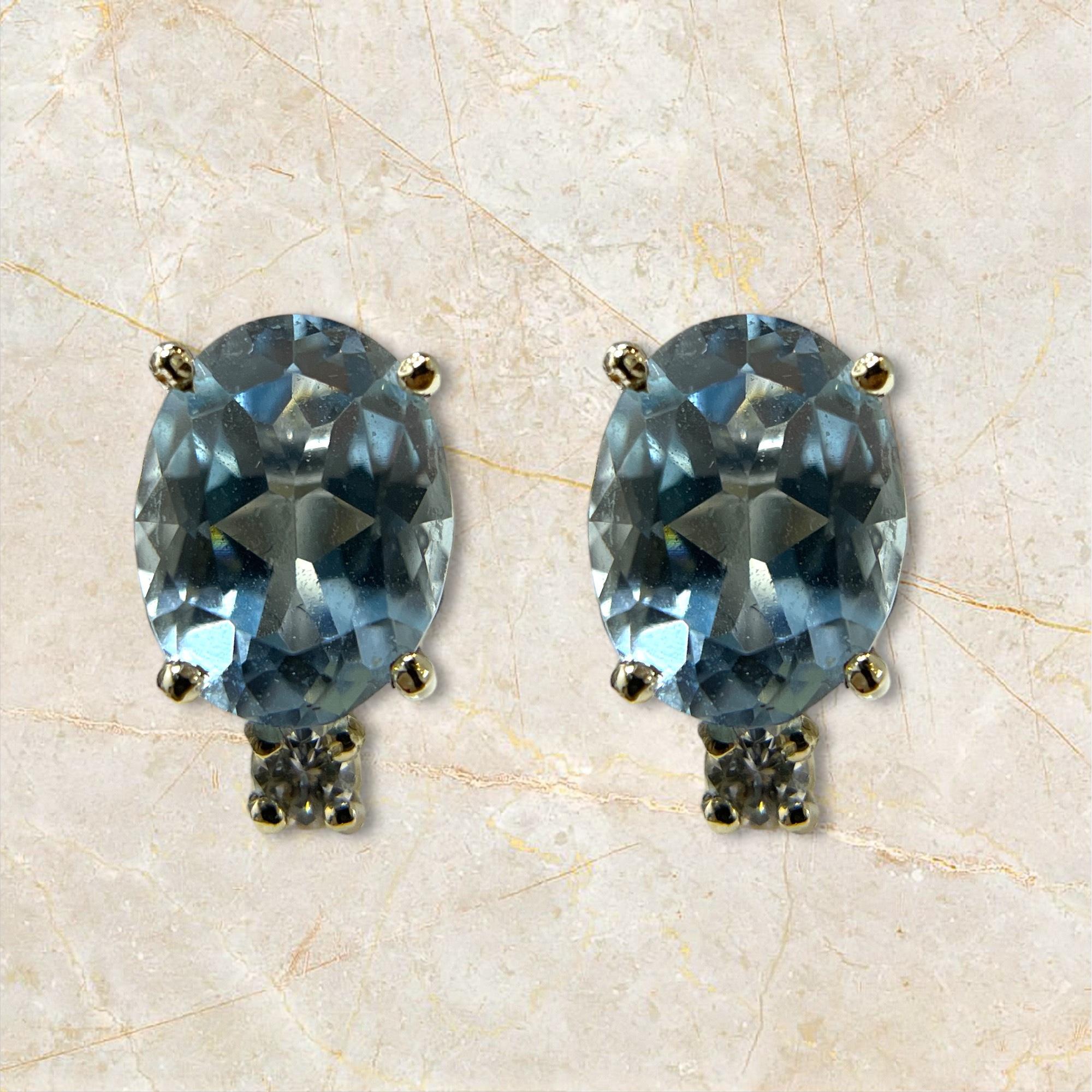 Questi splendidi orecchini a perno in oro bianco 14K sono caratterizzati da affascinanti gemme ovali di acquamarina, ciascuna accentata da un diamante scintillante. La fresca tonalità blu dell'acquamarina abbinata alla brillantezza dei diamanti crea