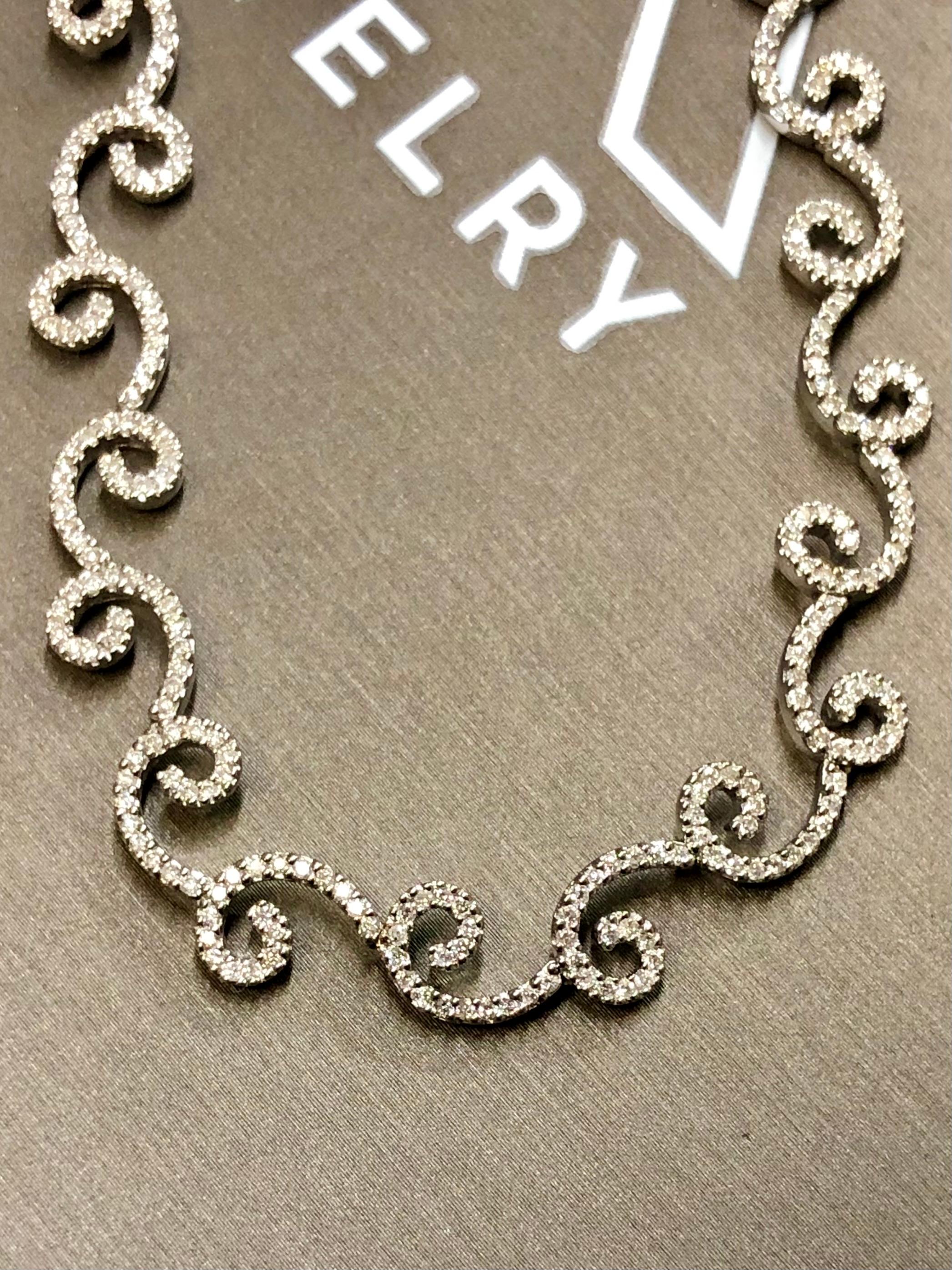 An elegant and wearable necklace done in 14K white gold, prong set with approximately 4.42cttw in H-J color Si1-I1 clarity round diamonds in a contemporary swirl design. Lays beautifully on the neck and the quality of manufacturing is apparent when