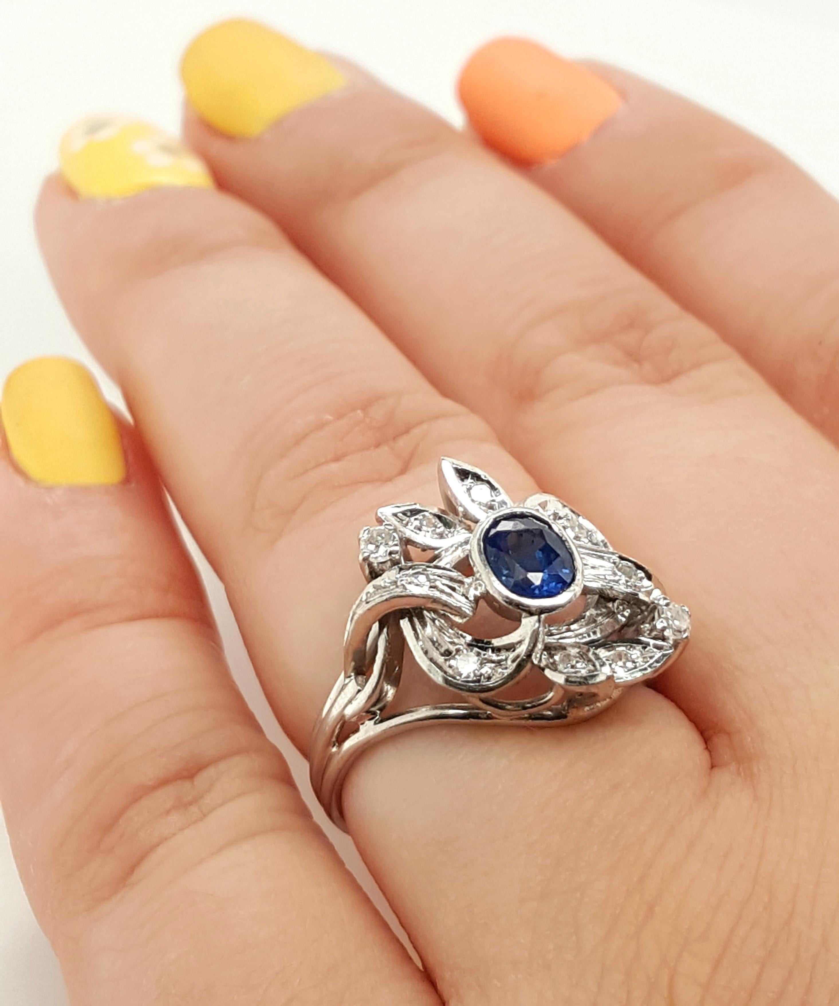 Estate 14 Karat White Gold Oval Blue Sapphire and Diamond Cocktail Ring.  The ring feature a lovely oval shaped blue sapphire.  The stone is set into a 14 karat white gold bezel enhanced by an ornate pattern of single cut diamonds and gold, with a