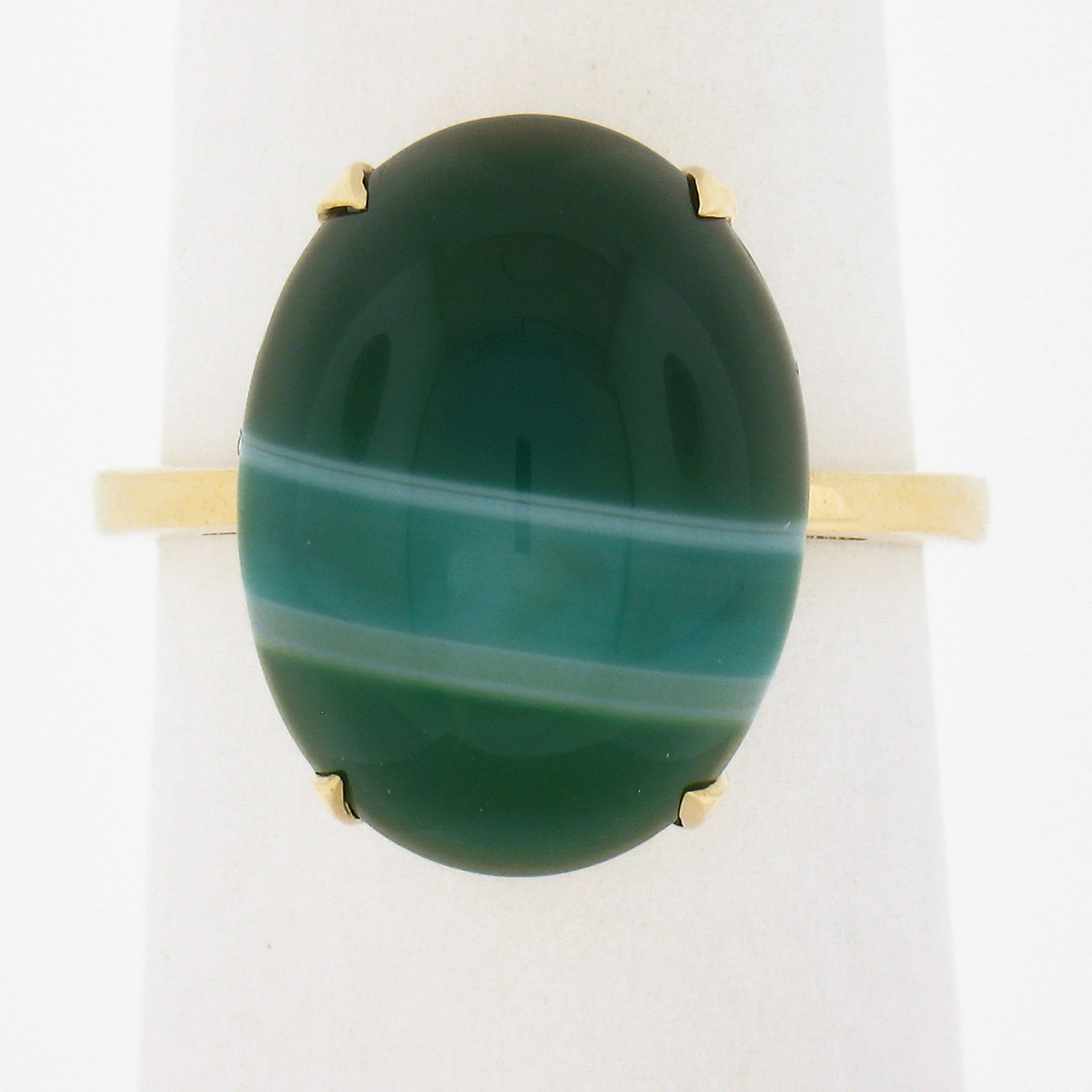 This classy solitaire ring was crafted in solid 14k yellow gold features an adorable oval cabochon banded agate neatly prong set at its center. The agate shows a wonderful green color with white lines. This ring is in like new condition and is a