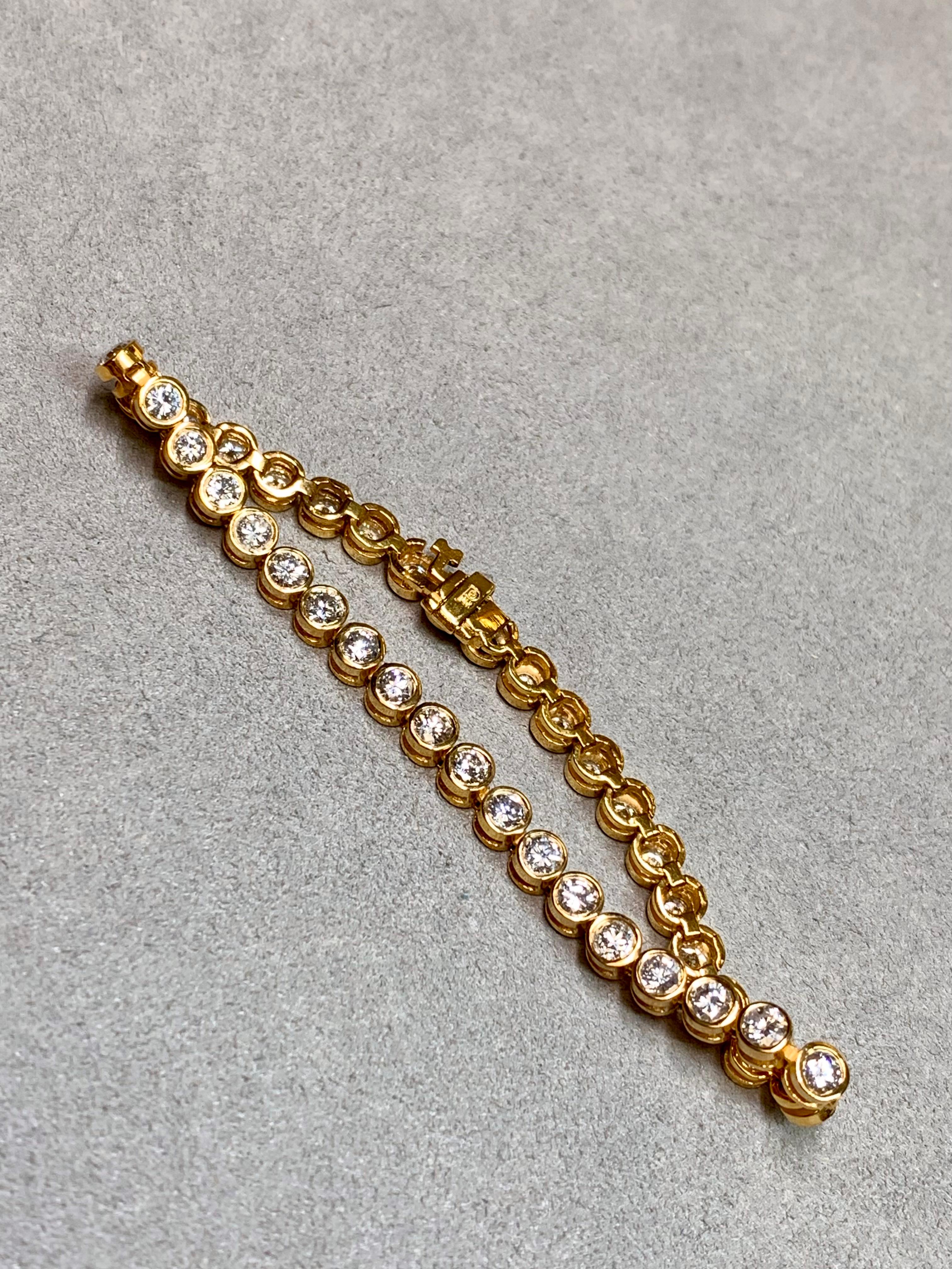 
Una pulsera tenis refinada y bellamente articulada, elaborada en rico oro amarillo intenso de 14 quilates. El diseño presenta treinta y ocho diamantes brillantes redondos de talla completa, cada uno engastado individualmente en bisel en marcos