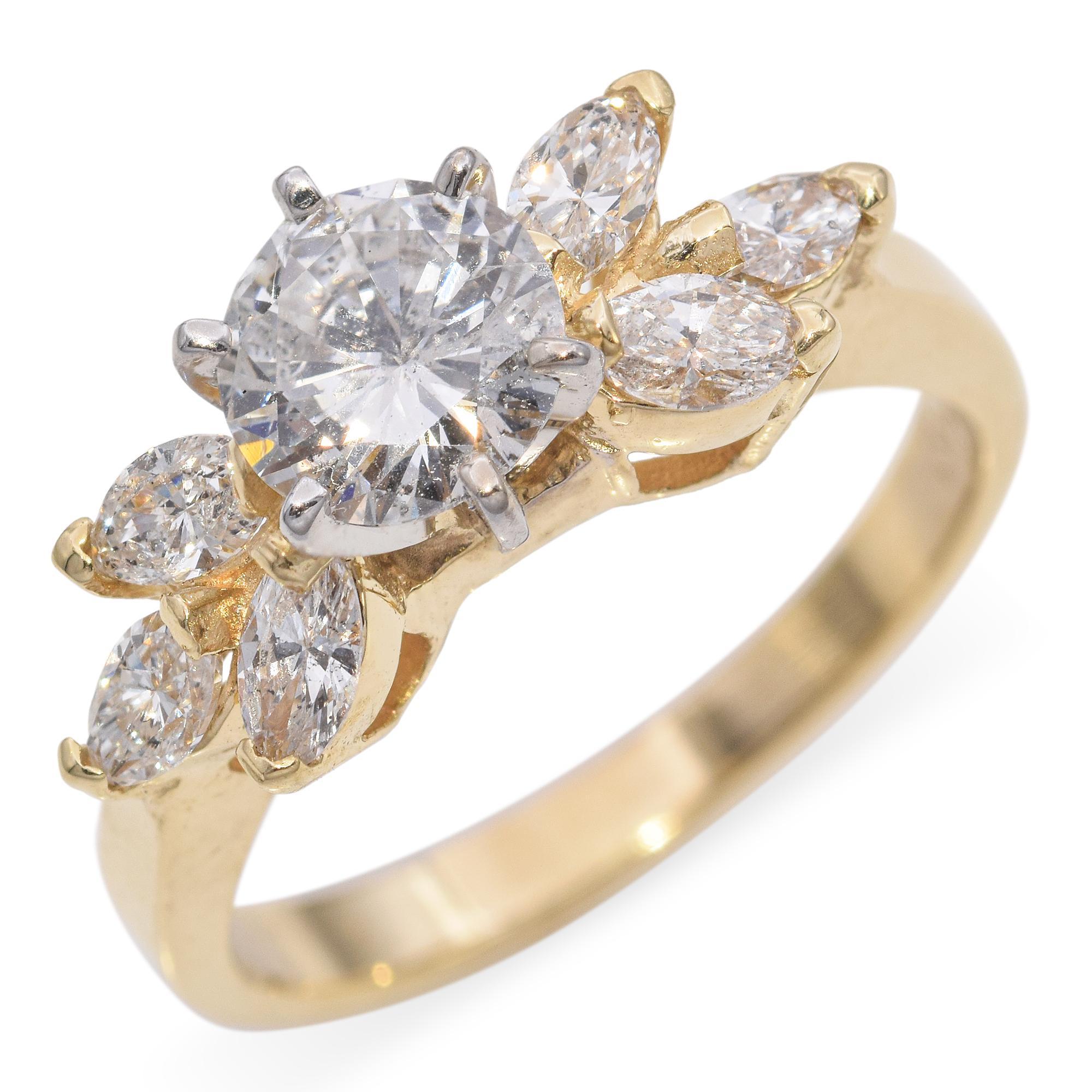Cette bague frappante est ornée d'un diamant central rond de taille brillant, flanqué de diamants de taille marquise et ronde, méticuleusement sertis dans une combinaison d'or blanc et d'or jaune. Le design complexe présente un motif floral, les