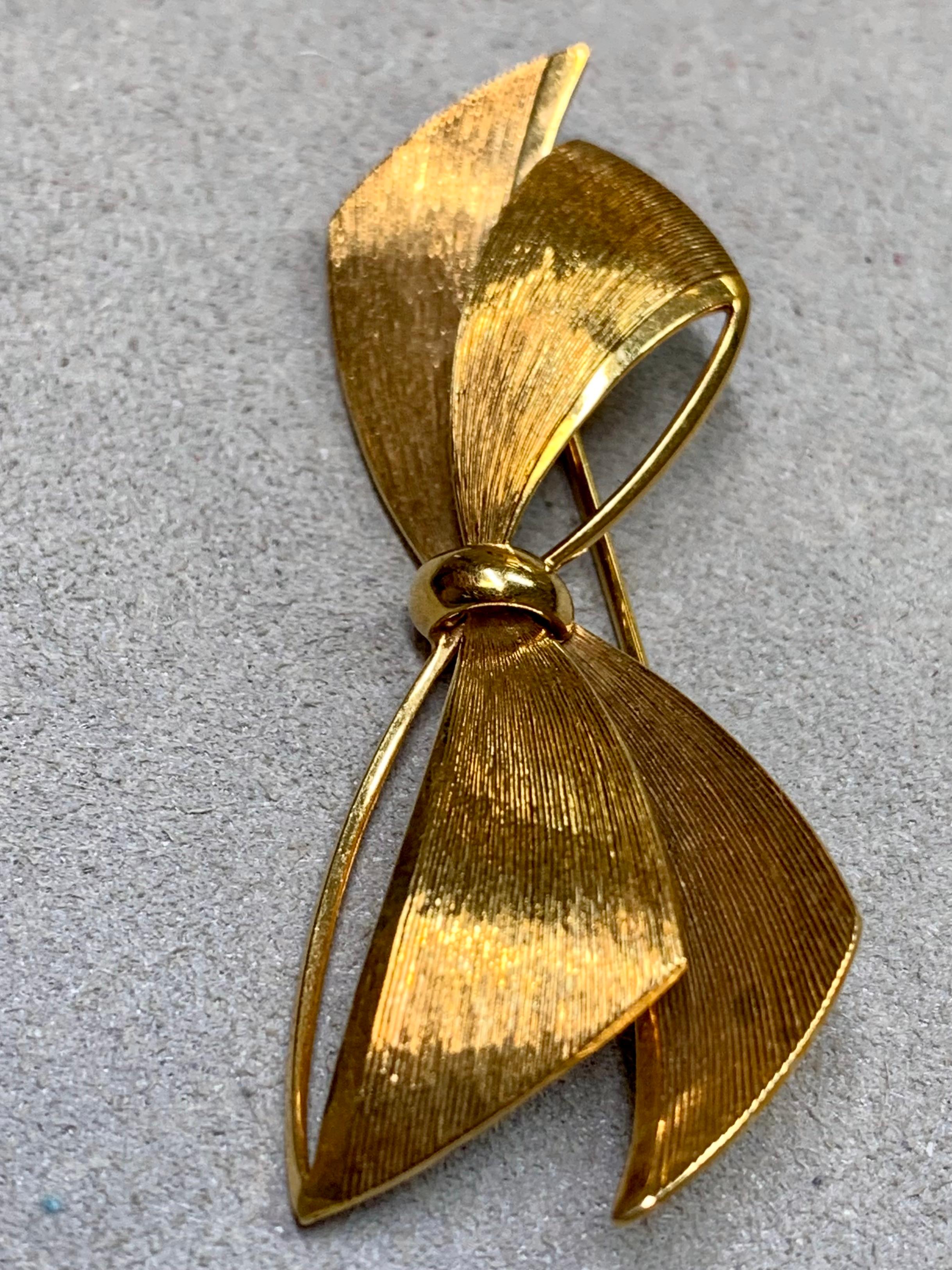 
A vintage bow-shaped pin by Tiffany & Co., crafted circa the 1980s in Germany. This elegant piece features Tiffany’s signature line-textured finish in rich 14 karat yellow gold, formed into a graceful ribbon design. A timeless and collectible