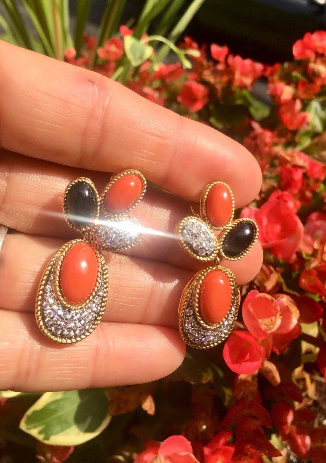 These stunning estate high end dangle earrings are set in 18 karat gold (tested) with lovely medium orange coral and black onyx gemstone cabochons.

Earrings are also set with 74 round diamonds totaling approximately 1.50 carats of G/VS brilliant