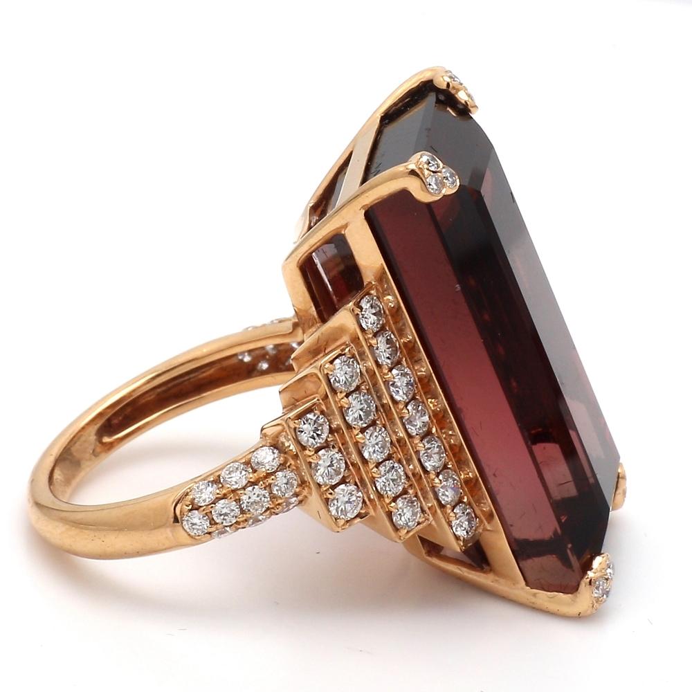 18K rose gold, cocktail ring.  Center stone is one (1) emerald cut red tourmaline weighing 34.77ct. Tourmaline measures approximately 26mm x 13mm. Ring is set with sixty-two (62) round brilliant cut diamonds weighing approximately 1.25ctw. Ring