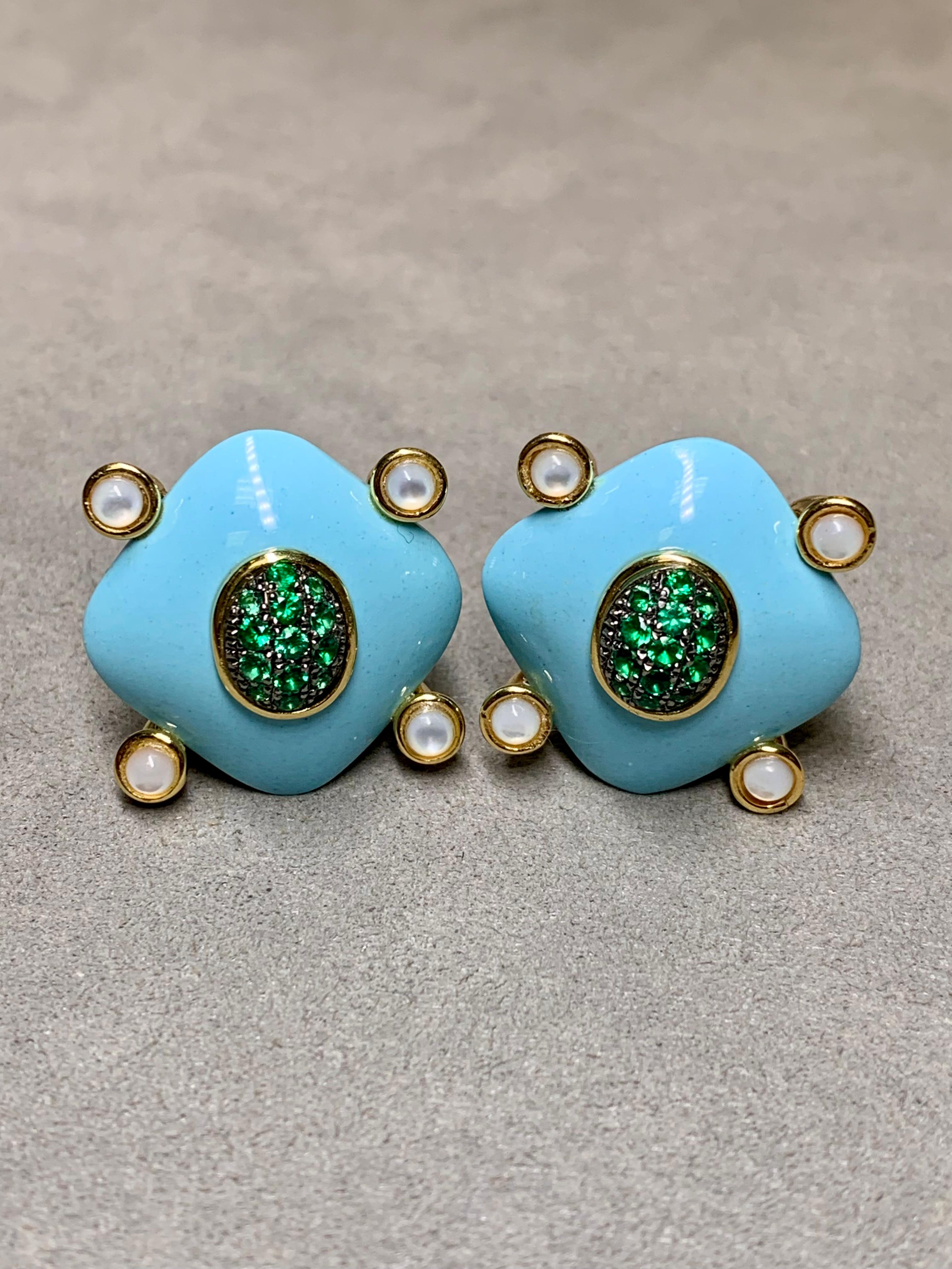 A clean, bold and elegant pair of finely made huggie earrings crafted in 18K yellow gold and centered by large, carved pieces of natural turquoise centered by round cut natural emeralds and carefully finished with cabochon moonstone on each corner.