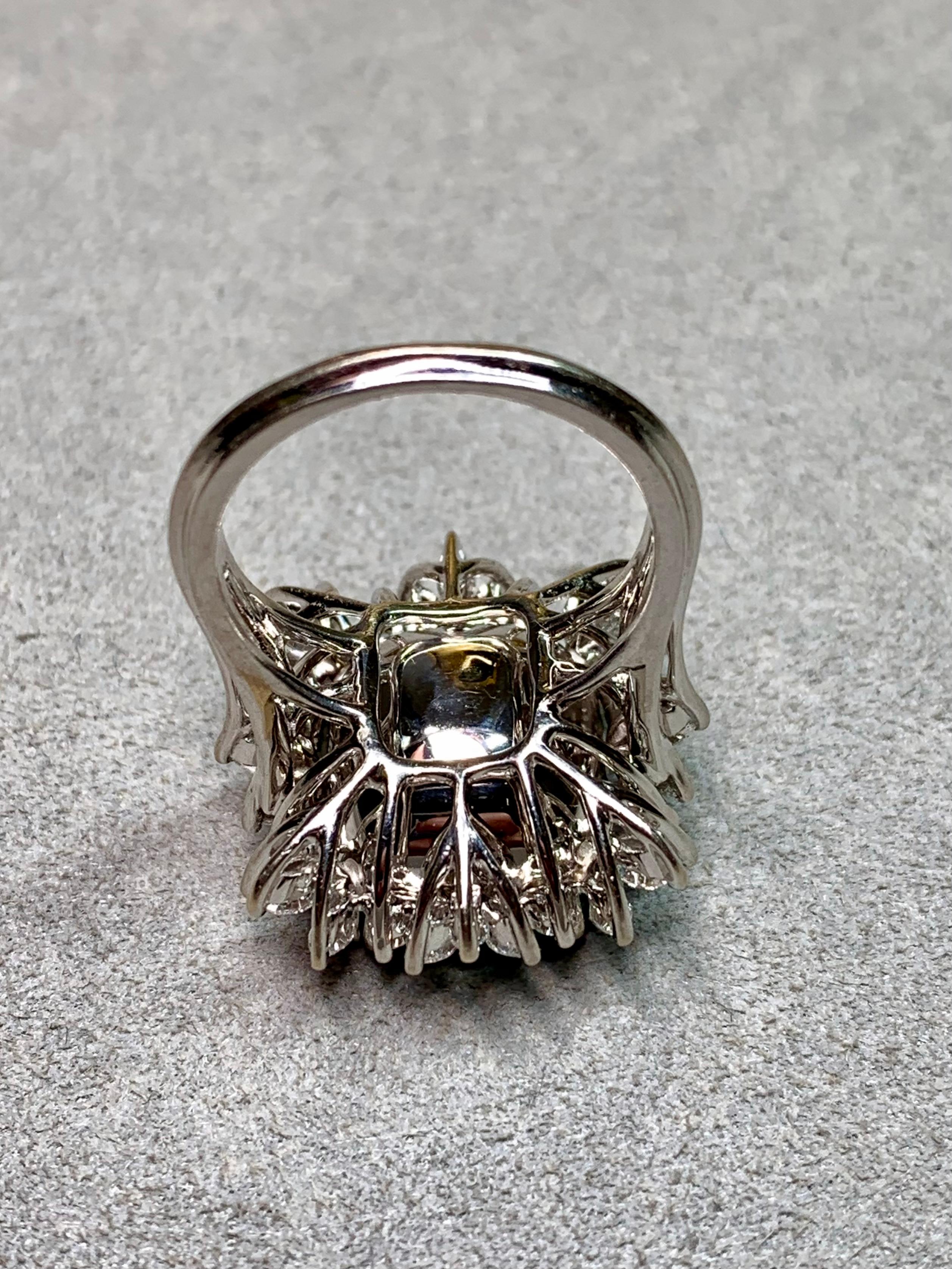 Un extraordinario anillo de esmeraldas y diamantes, elaborado en lujoso oro blanco de 18 quilates, con una imponente esmeralda natural talla cojín de 11,77 quilates como pieza central. La esmeralda muestra un verde brillante y saturado con un suave