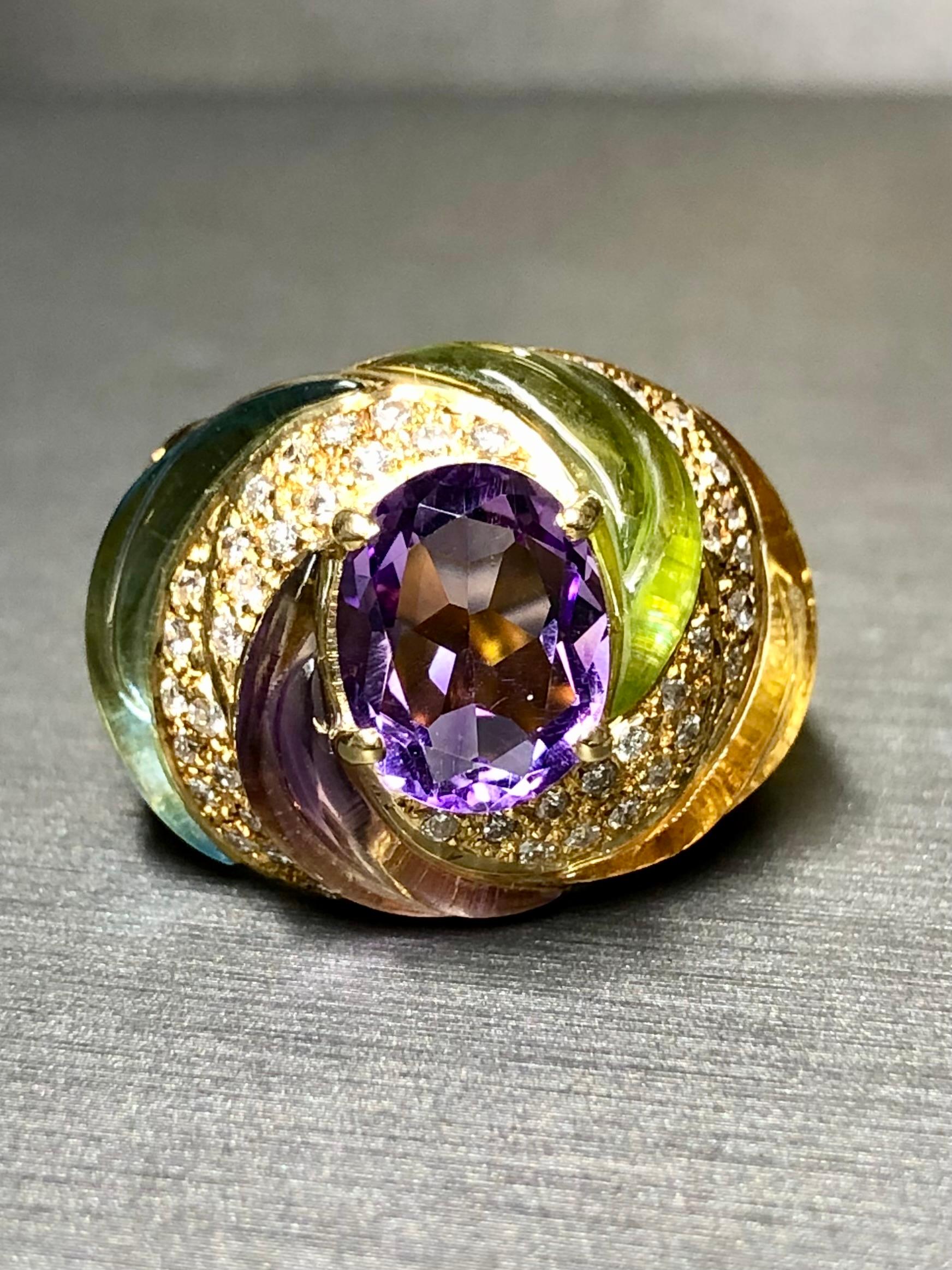 
Precioso cóctel único elaborado en oro amarillo de 18 quilates con incrustaciones de aguamarina y peridoto naturales bellamente tallados y centrado por una amatista ovalada natural de precioso color. En la parte superior hay 0,40 ctw de diamantes