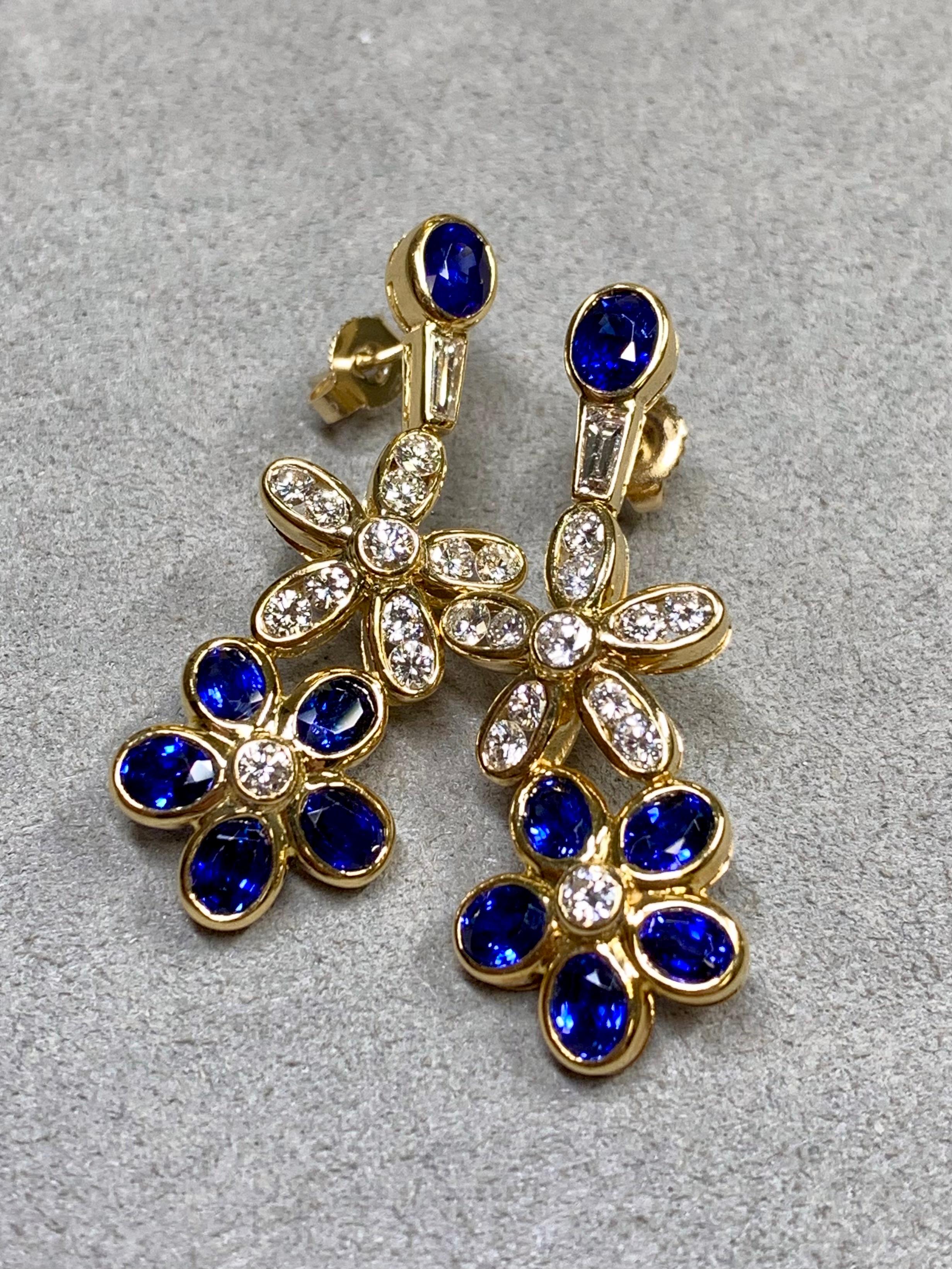 
Une superbe paire de pendentifs floraux en or jaune 18 carats, sertis en canal et en chaton d'environ 1,85ctw de diamants ronds et baguettes de couleur F-G Vs1-2 ainsi que de 4,30ctw de saphirs bleu royal de taille ovale plus importante. Ces
