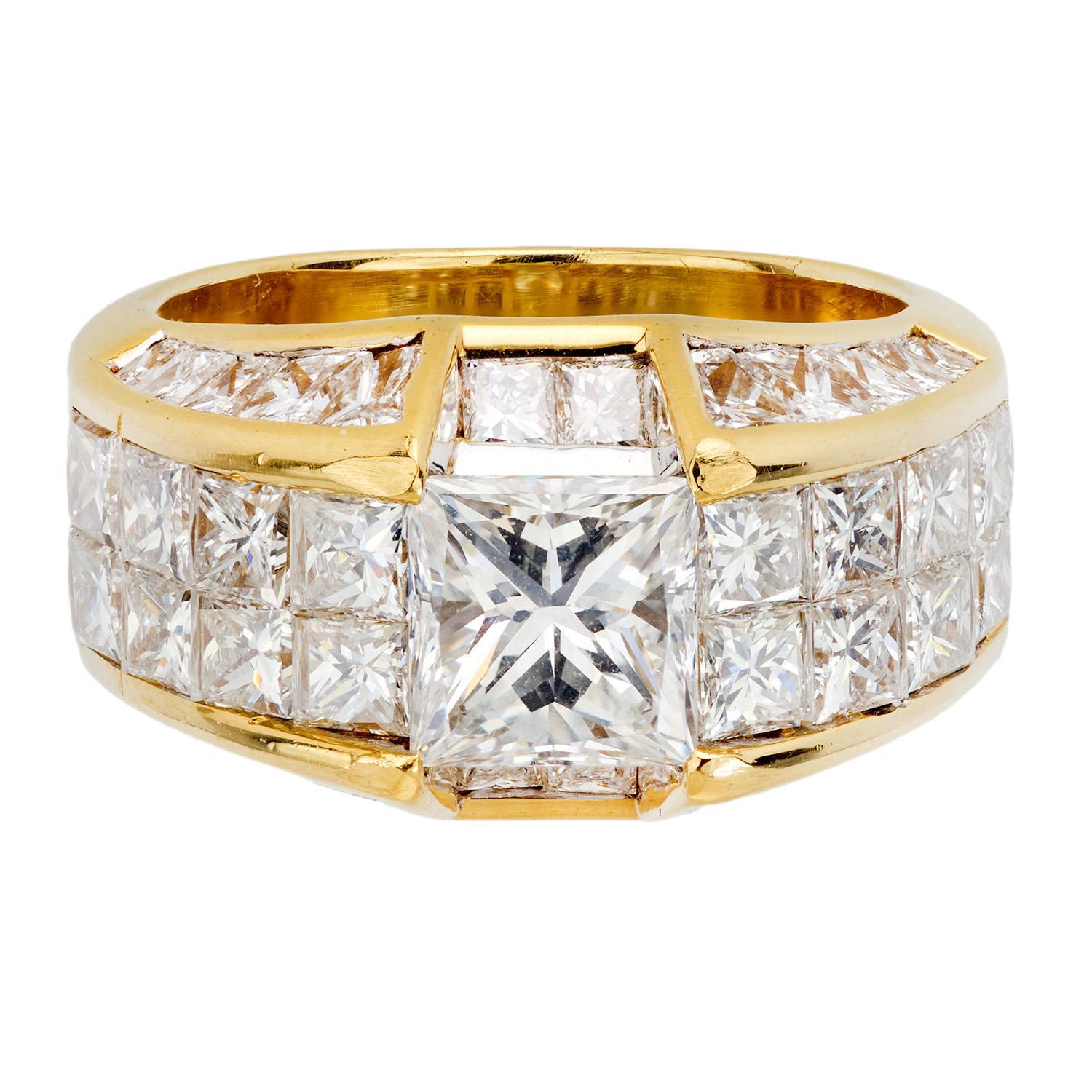 A fabulous and bold diamond ring! Crafted in vibrant 18k yellow gold, this elaborate ring features a large central princess cut diamond, which is invisibly set. The stone has a carat weight of 1.56ct, and displays G color and VS2 clarity. The front
