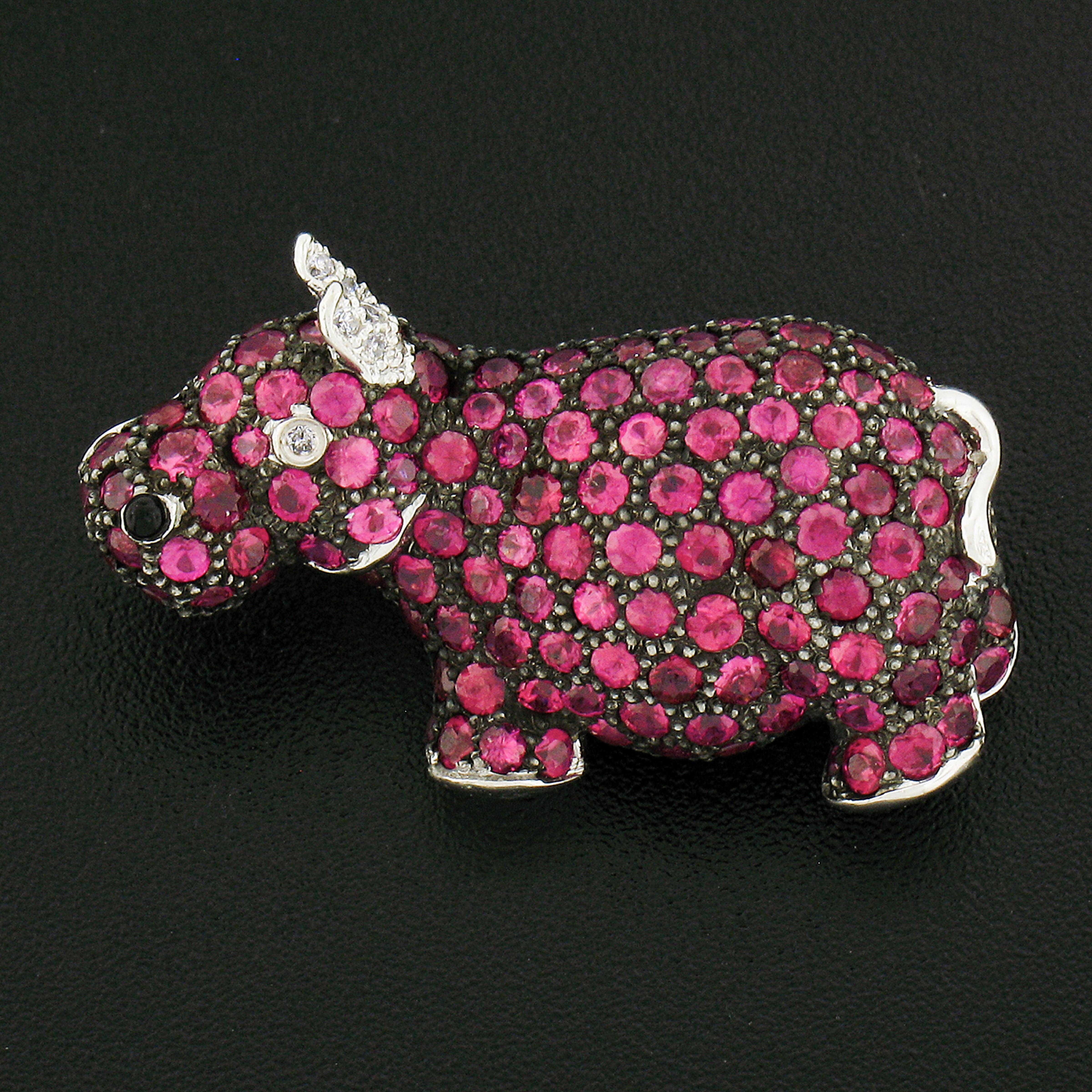 This super adorable hippopotamus brooch is crafted in solid 18k white gold with black rhodium throughout. The entire hippo design is neatly pave set with super fine quality purplish red rubies and is also adorned with a few diamonds at its ears and