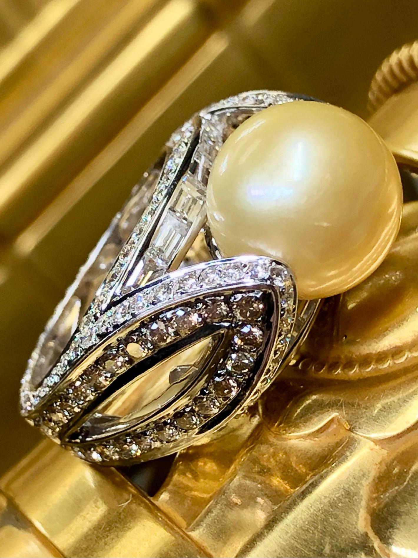 Un impressionnant cocktail contemporain réalisé en or blanc 18 carats et centré par une magnifique perle dorée des mers du sud mesurant 11,90 mm entourée d'environ 3ctw de diamants ronds et baguettes. Les diamants blancs sont en moyenne de couleur