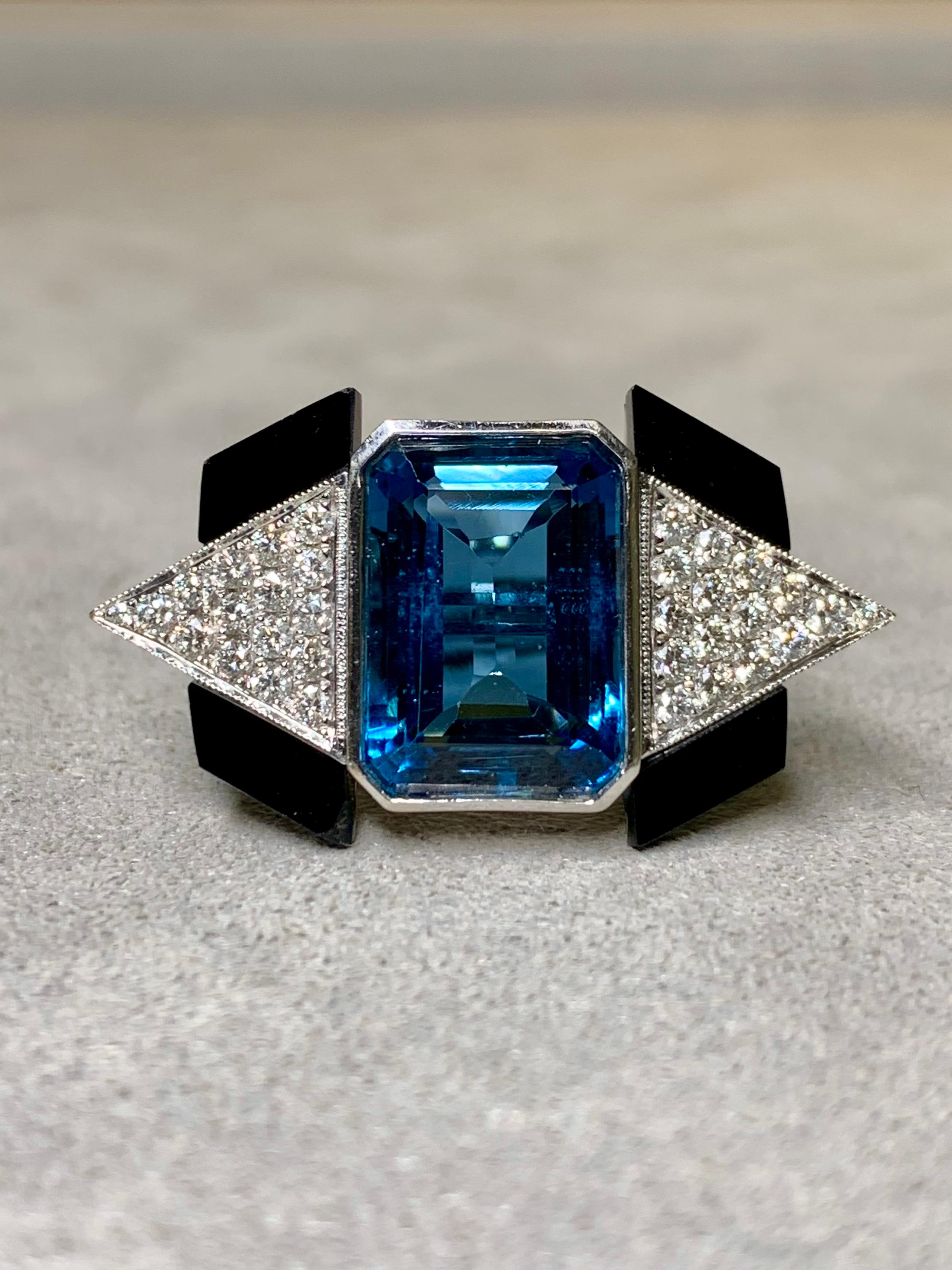 An absolutely gorgeous cocktail ring crafted in 18K white gold in a very Art Deco style. It is centered by a bezel set, deep London blue natural topaz weighing approximately 10ct which is flanked by approximately .60ctw in meticulously set and well