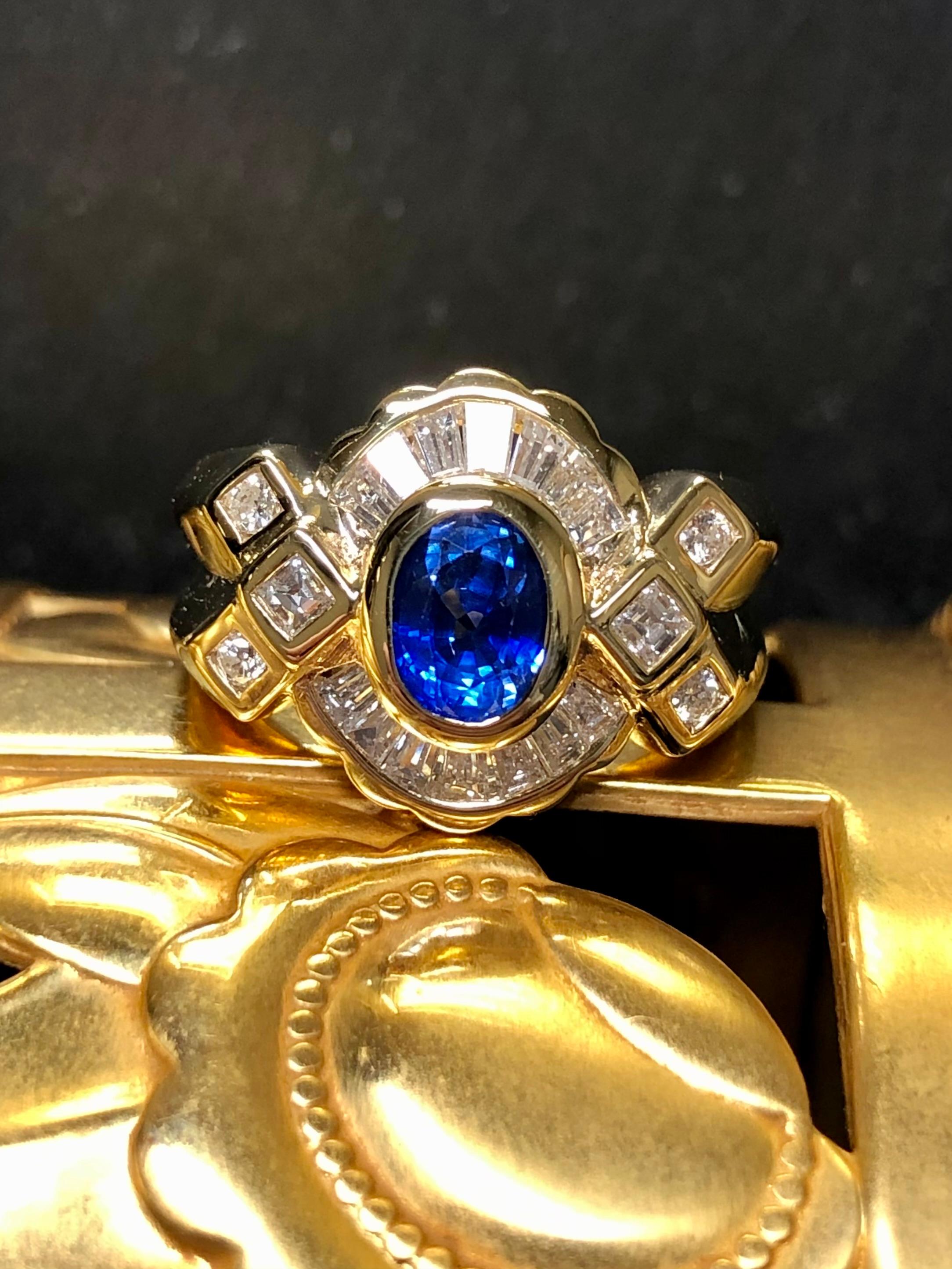 
A gorgeous ring done in supple 18K yellow gold and centered with a gorgeous royal blue natural bezel set sapphire weighing approximately .80ct surrounded by approximately 1.60cttw in tapered and square baguette as well as round