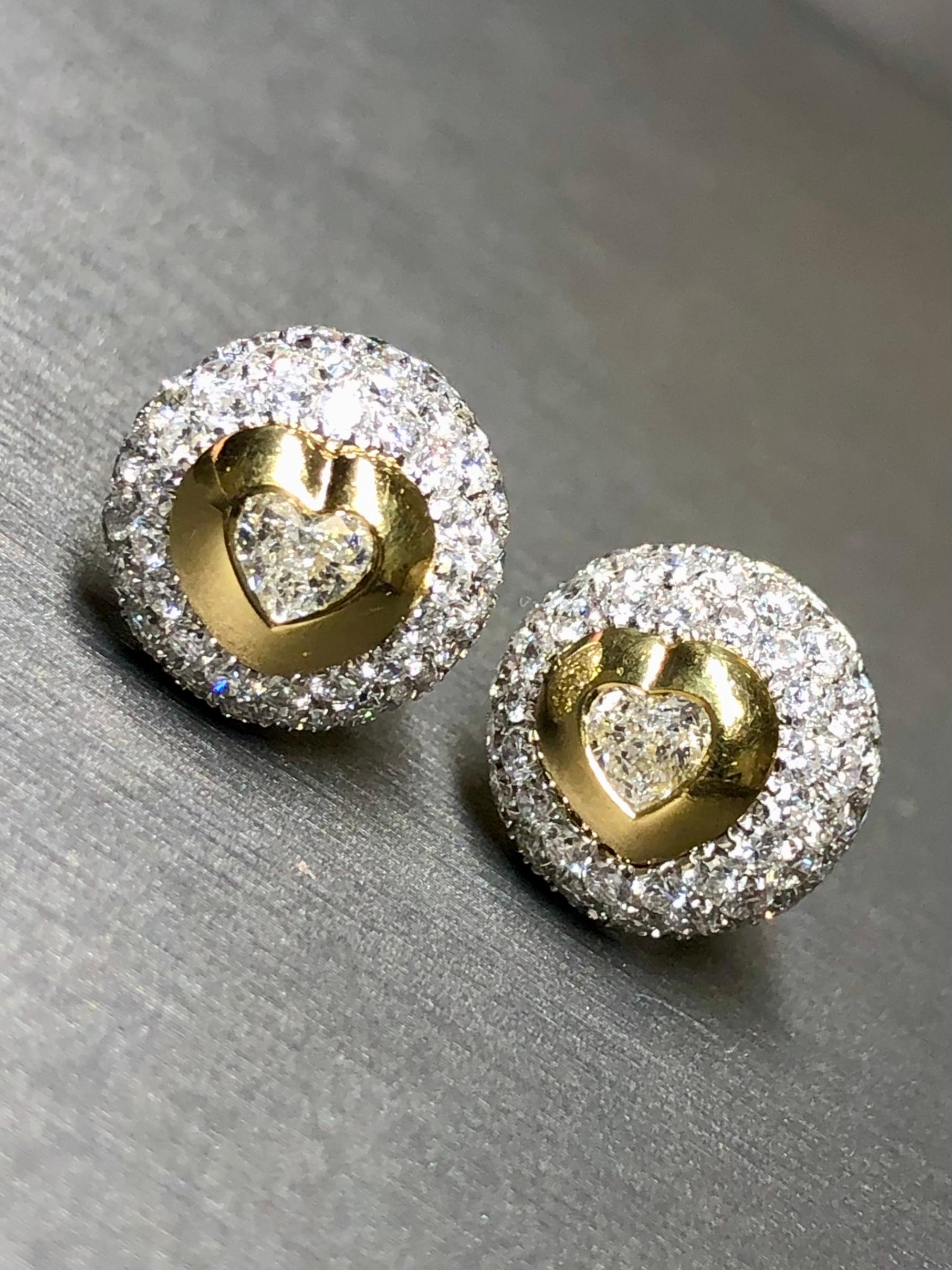 Finely made stud earrings crafted in 18K white and yellow gold meticulously set with approximately 2.84cttw in F-G color Vs1 clarity beautifully matched round diamonds and centered by .60cttw in larger heart shaped diamonds being G-H color and Vs1