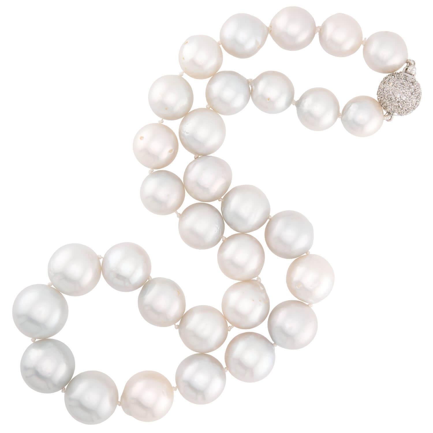 ¡Un elegante collar de perlas con un cierre espectacular! Este maravilloso collar está compuesto por perlas de 13 mm, anudadas individualmente y ensartadas en hilo blanco. Las perlas exhibidas varían ligeramente en tamaño y forma, pero muestran un