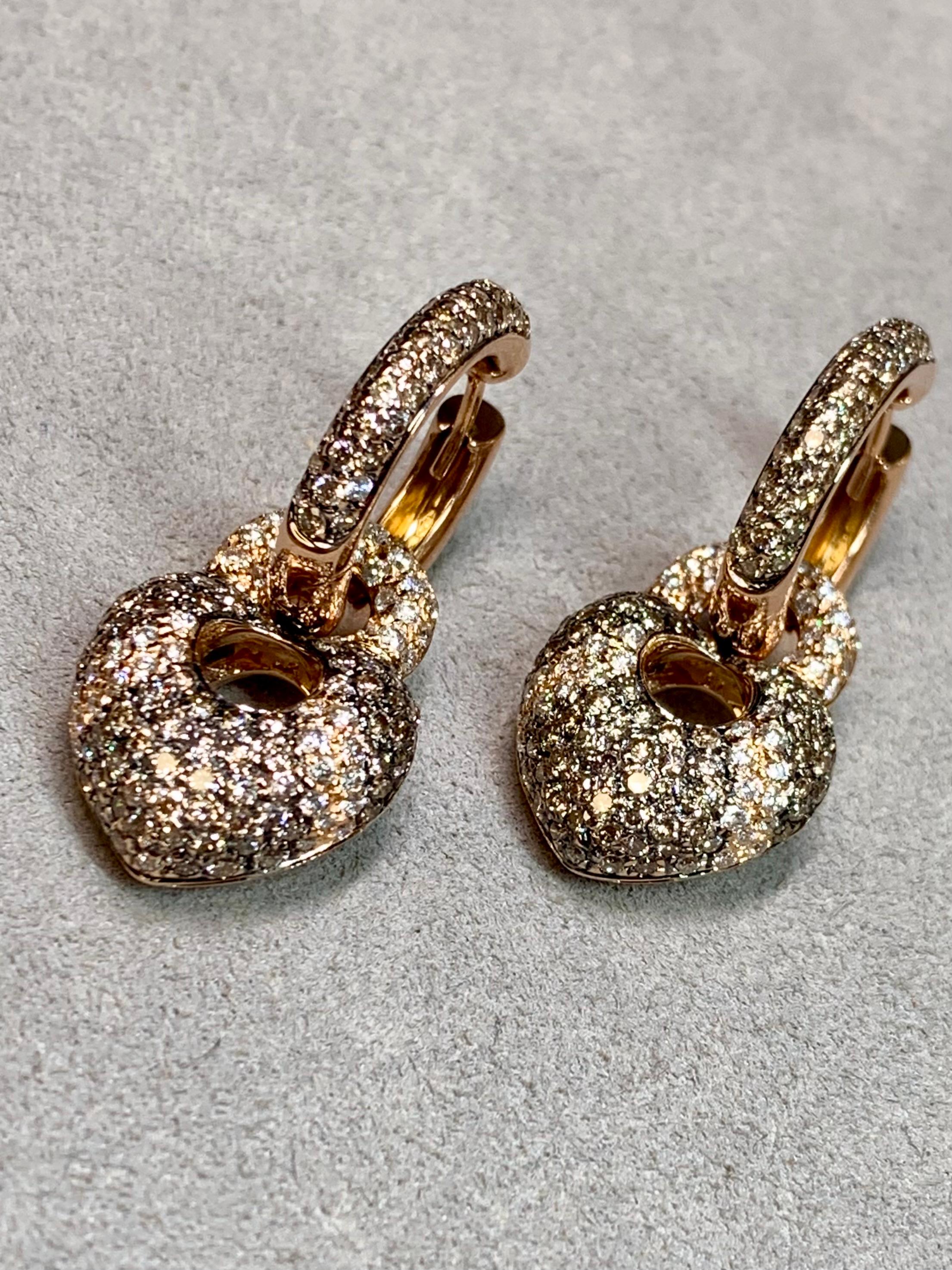 These beautifully crafted contemporary drop earrings are done in rich 18 karat rose gold and showcase a bold yet refined design. Each earring features a diamond-set hoop suspending a luxuriously puffed heart drop, fully pavé-set for exceptional