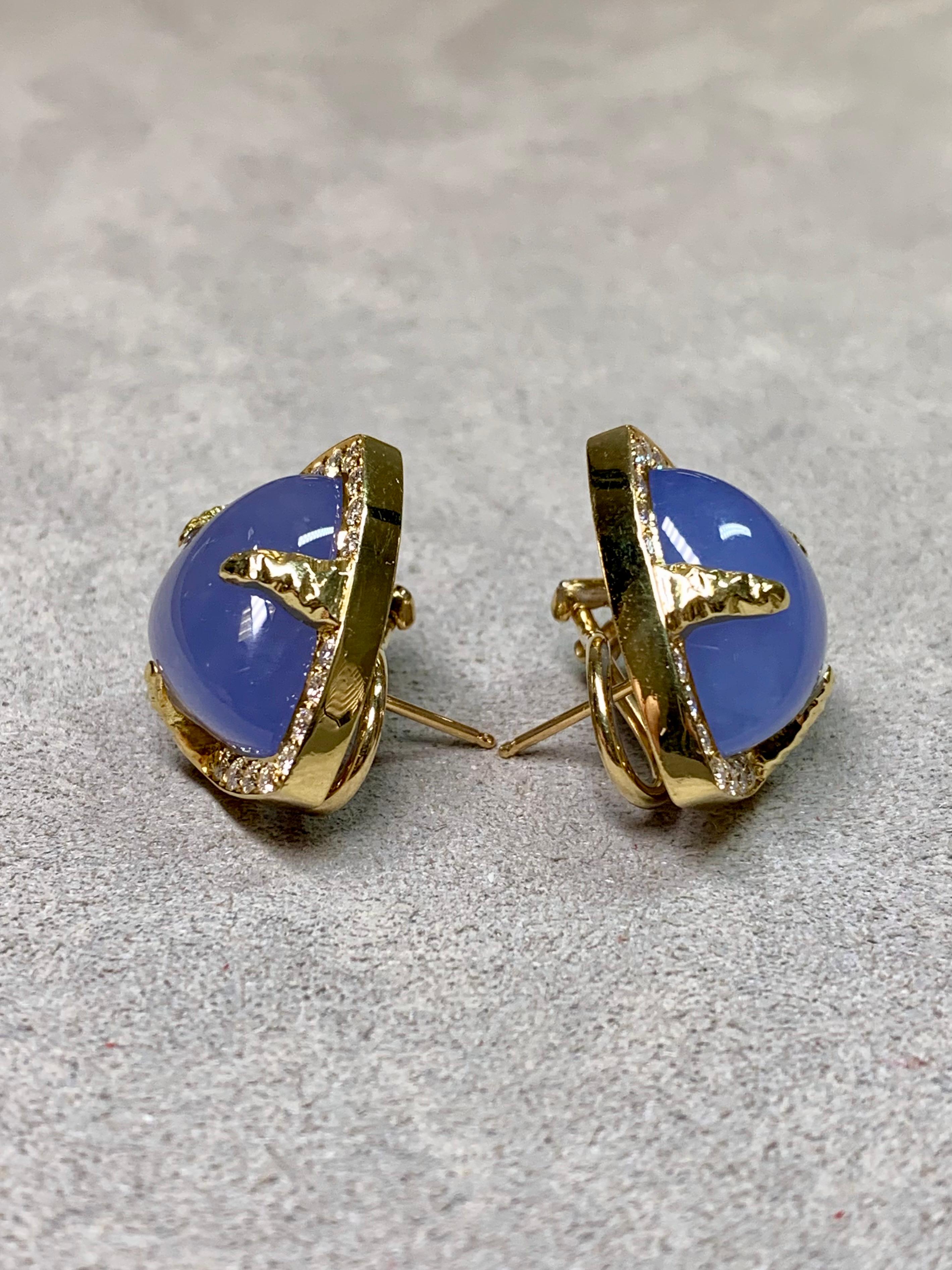 Cette paire de boucles d'oreilles est magnifiquement réalisée en or jaune 18 carats et centrée sur un cabochon de calcédoine d'une douce teinte lavande. Chaque pierre est encadrée par un halo scintillant de diamants ronds finement assortis, créant