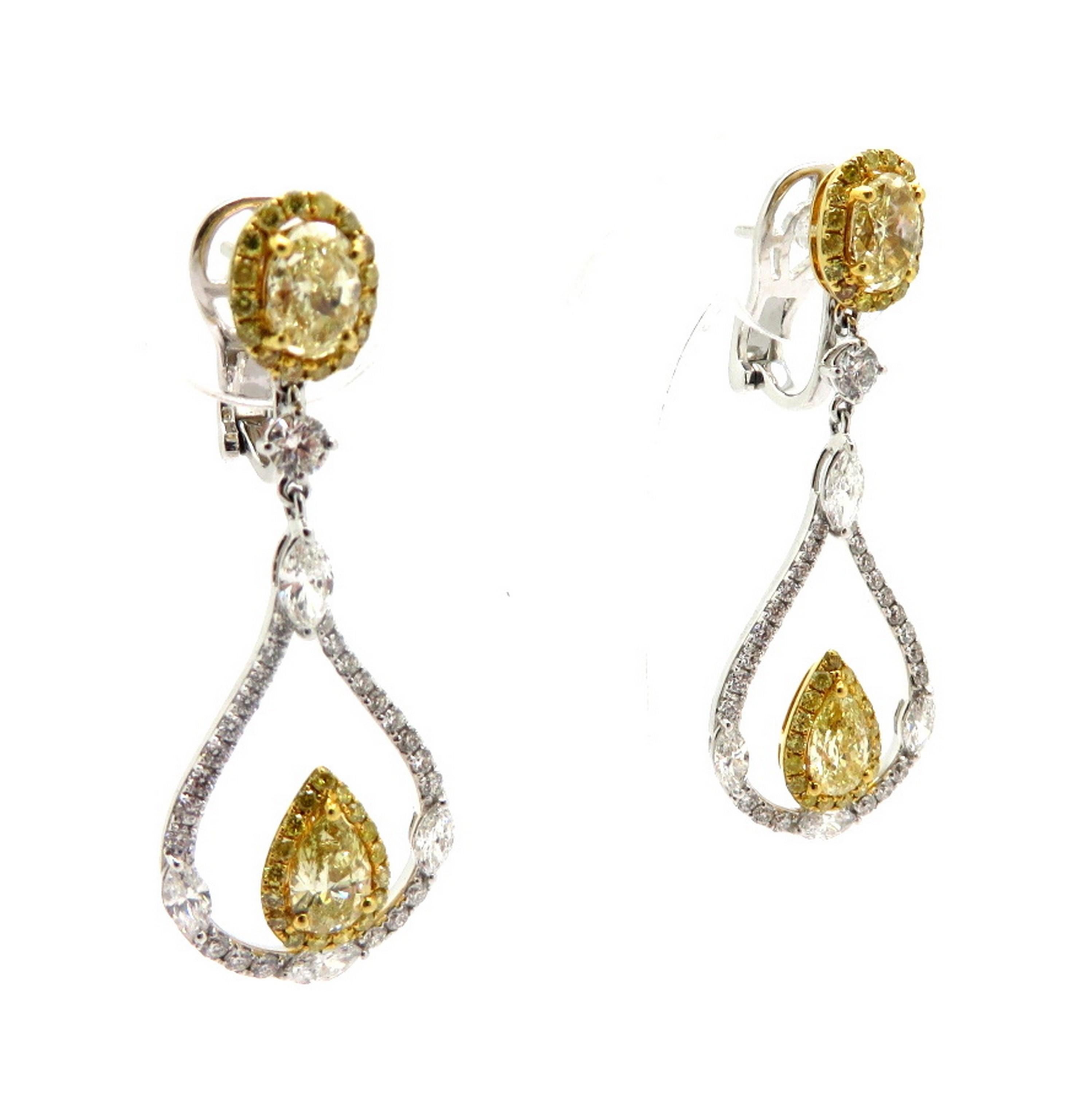 Estate 18K two-tone gold yellow and white diamond tear drop dangle fashion earrings. Showcasing 2 fancy yellow pear shaped diamonds, three prong set, weighing a total of 1.04 carats. Accented with two oval brilliant cut fancy yellow diamonds, four